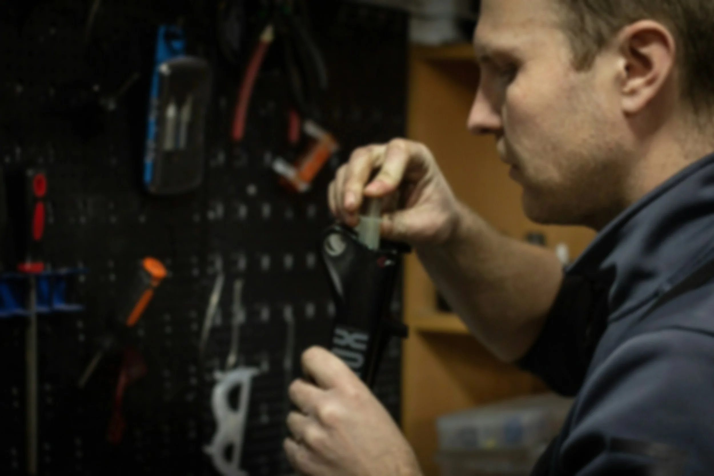 A man working on electrical wiring or equipment in a workshop or garage setting.