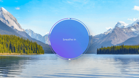 A tranquil mountain lake with a clear blue sky, tall mountain peaks, and dense green trees, overlaid with a circular graphic containing the words "breathe in."