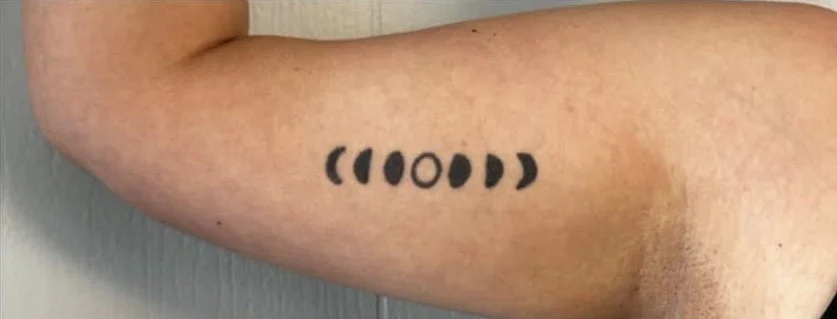 Tattoo of moon phases on a person's arm.
