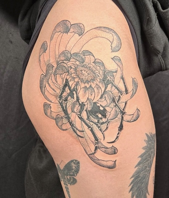 A tattoo of a detailed crab combined with a blooming flower on a person's upper arm.