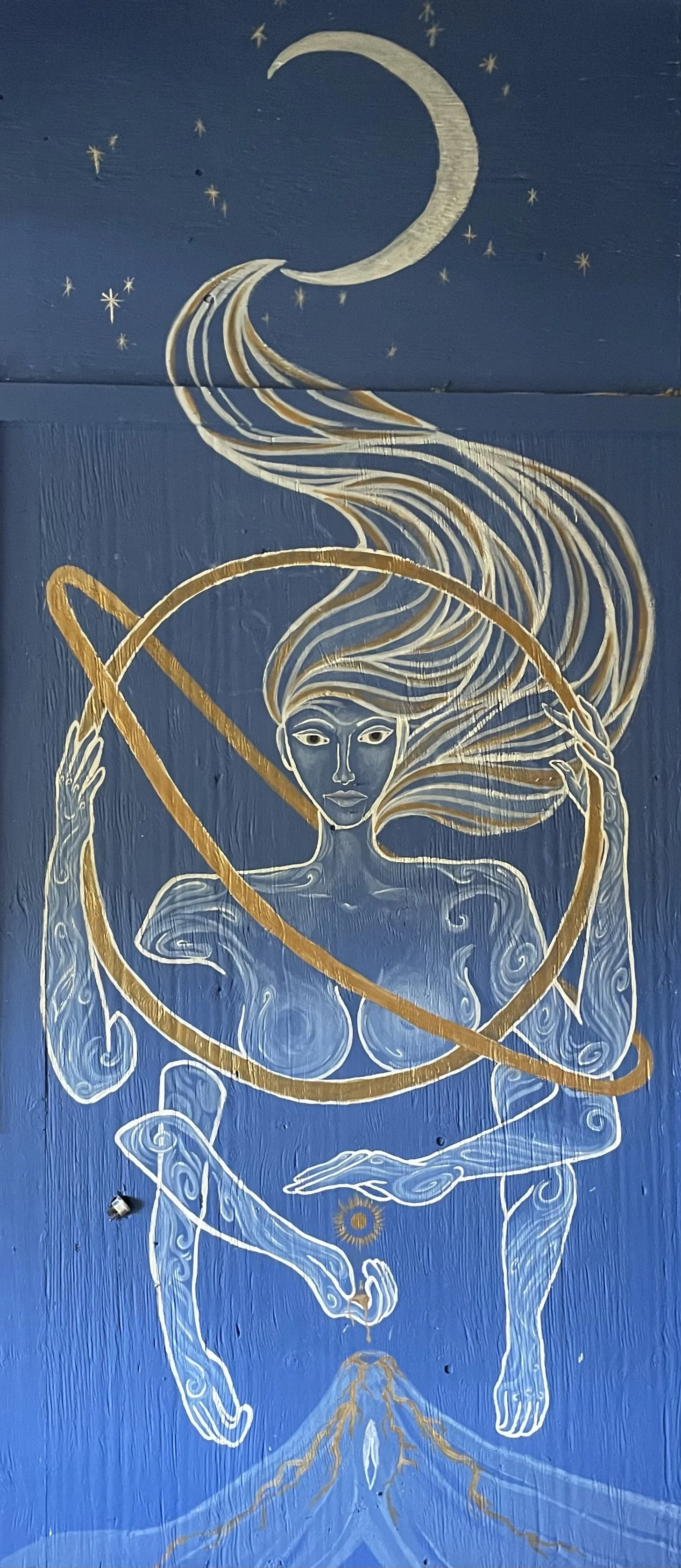 A mural of a stylized woman with flowing hair, a celestial background with a crescent moon and stars, and abstract patterns in white and gold on a blue background.