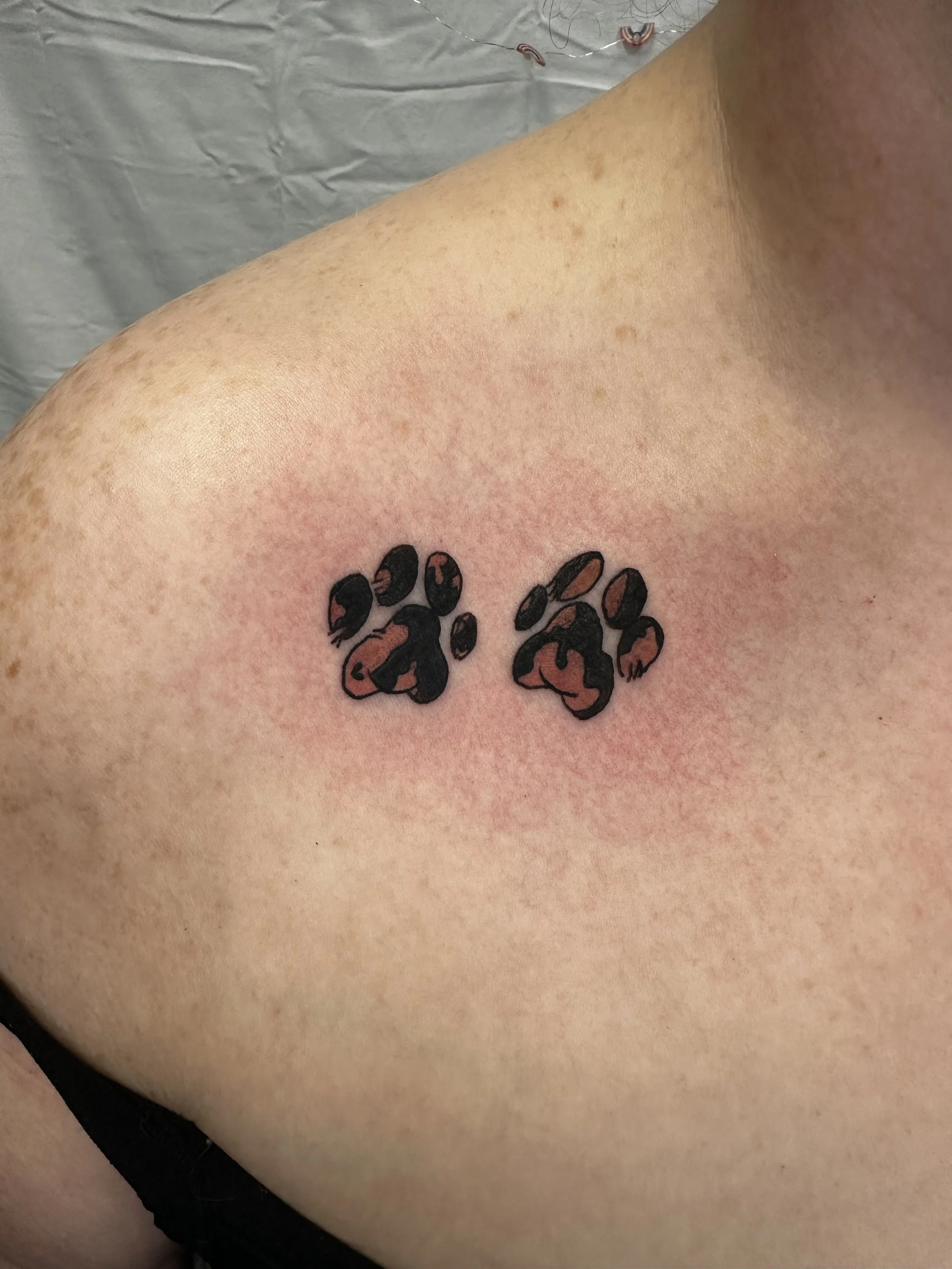 Close-up of a person's skin with a black and orange paw print tattoo.