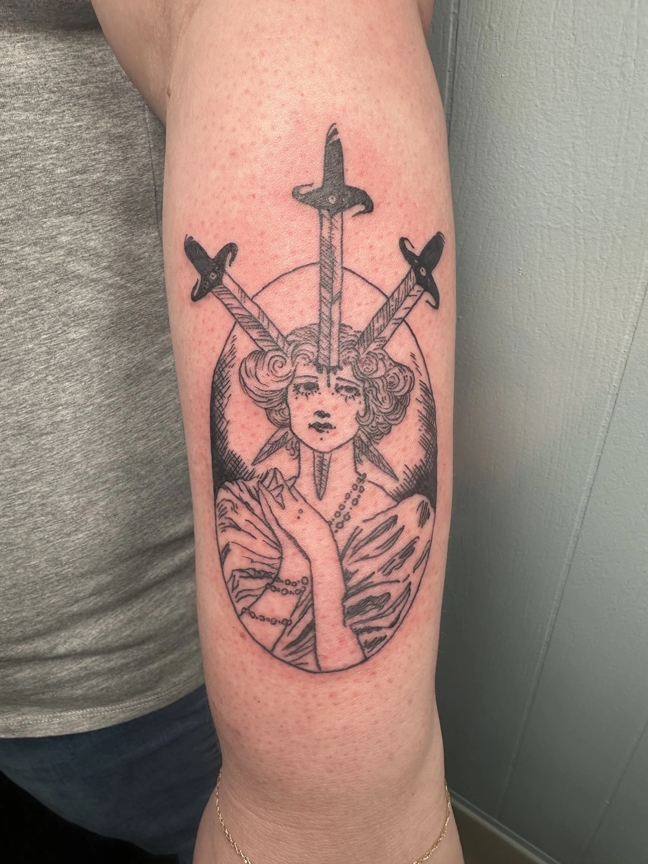 Tattoo of a woman with a necklace and meditative pose, with three swords above her head.
