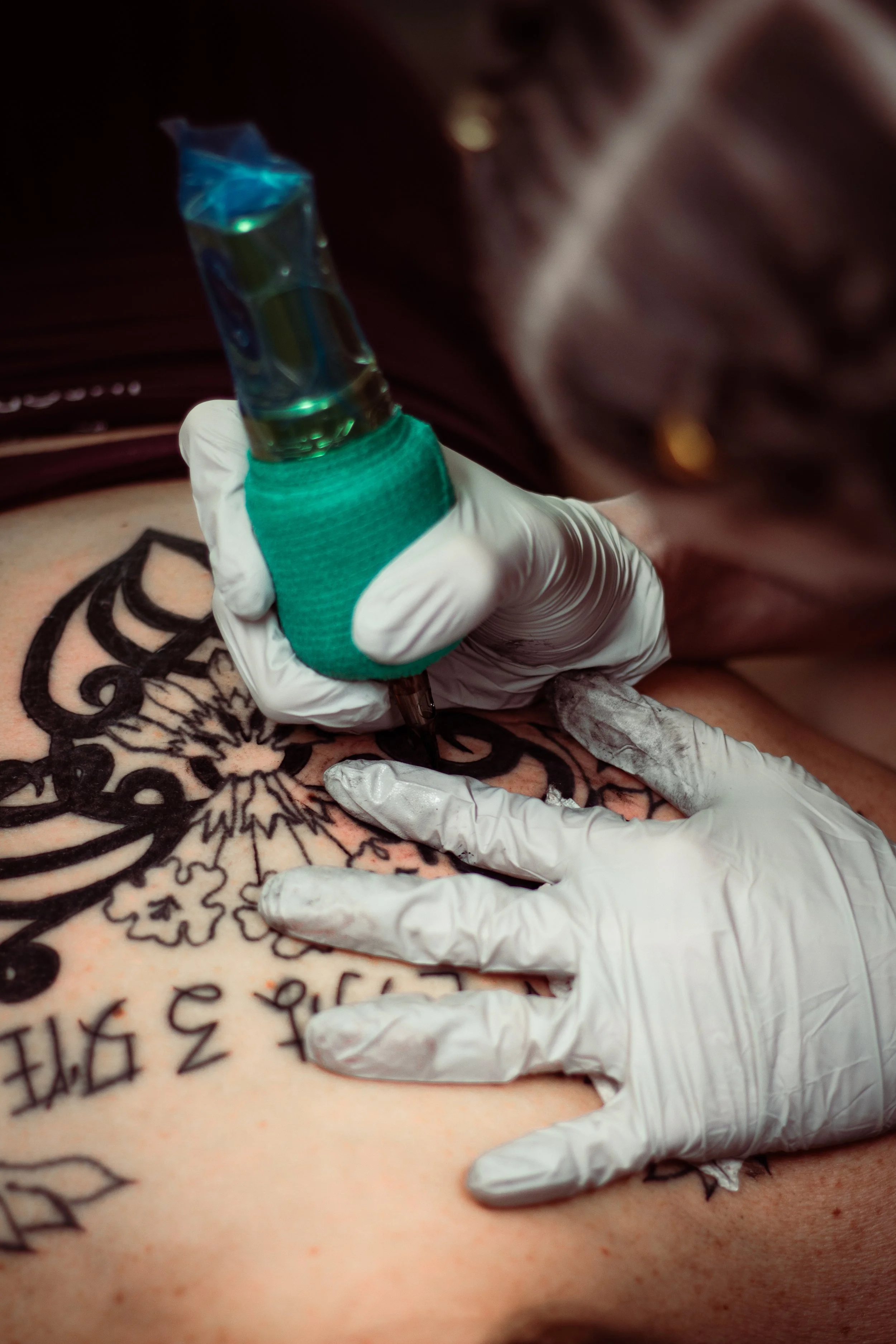 A person with a Disney-themed tattoo on their skin is receiving a tattoo session. The tattoo design includes a Mickey Mouse silhouette with intricate details.
