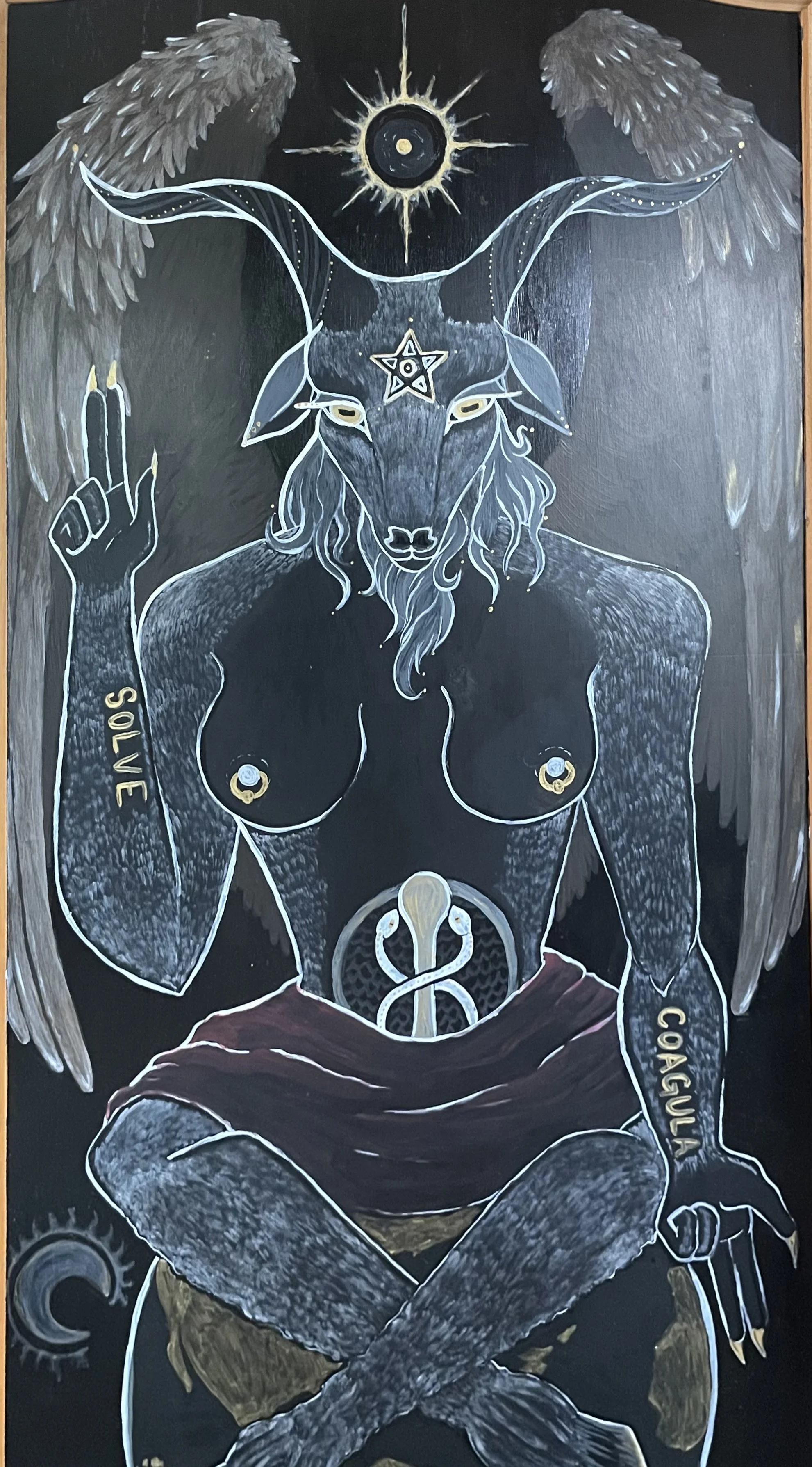A black chalkboard-style illustration of a goat-human hybrid with angel wings, a sun and moon symbol above its head, and various symbols and words on its body, including 'SOLVE' on its left arm and 'COGULI' on its right arm, depicted in a mystical or