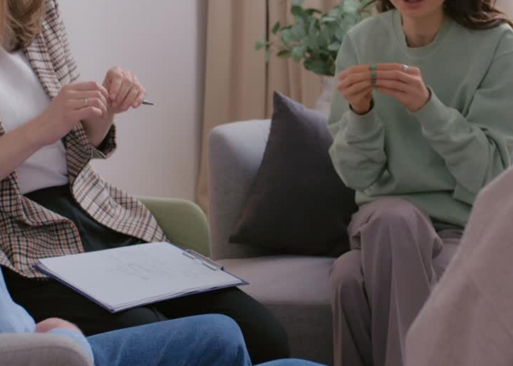 People sitting in a meeting room, with notebooks and papers on the table, engaged in discussion.
