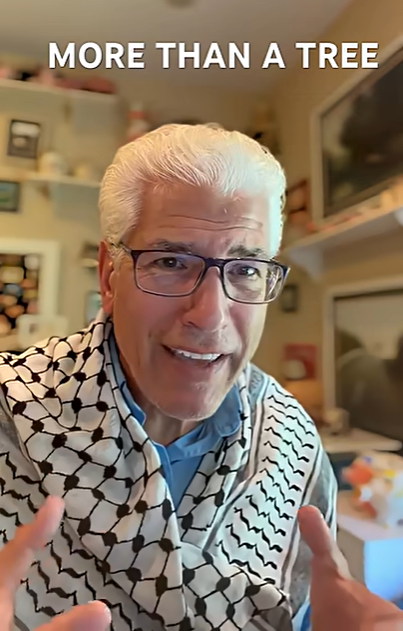 A man with white hair and glasses, wearing a patterned scarf, speaking in a room with shelves and televisions in the background, with the text "More Than a Tree" at the top.