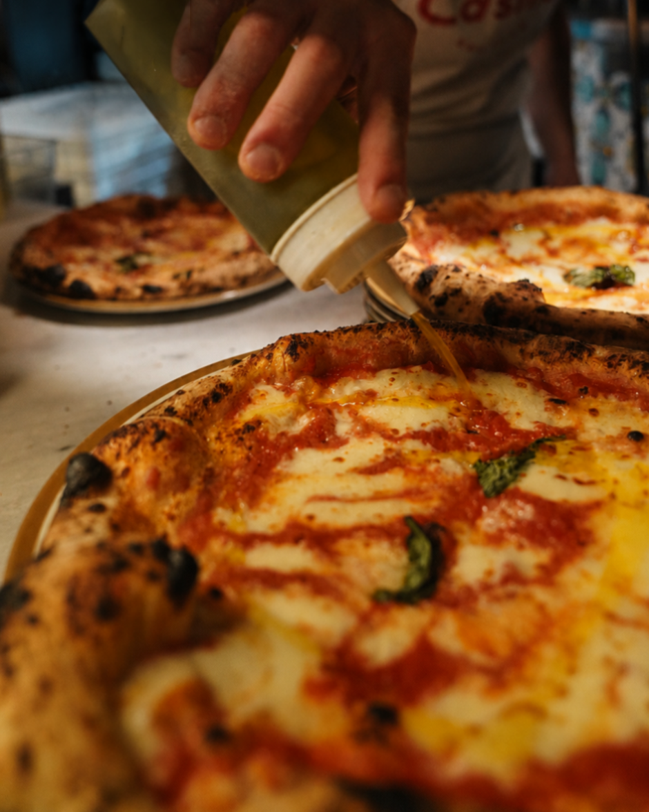 Close up of pouring Olive Oil at our Margherita Pizza