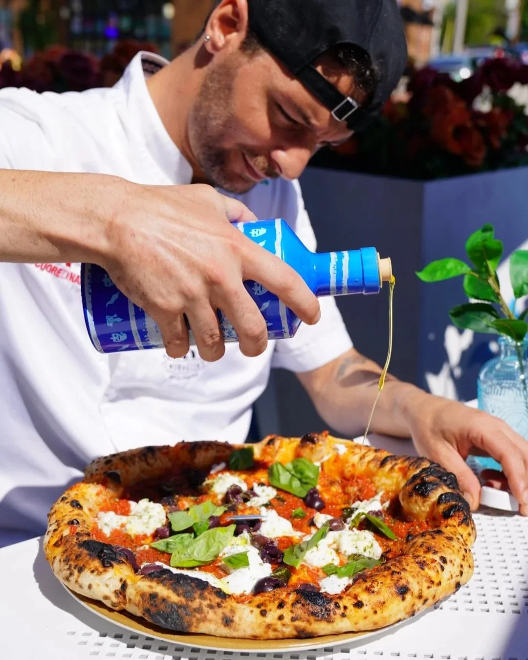 Pizzaiolo at Rutherford, NJ Pouring Extra Virgin Olive Oil at our Margherita pizza