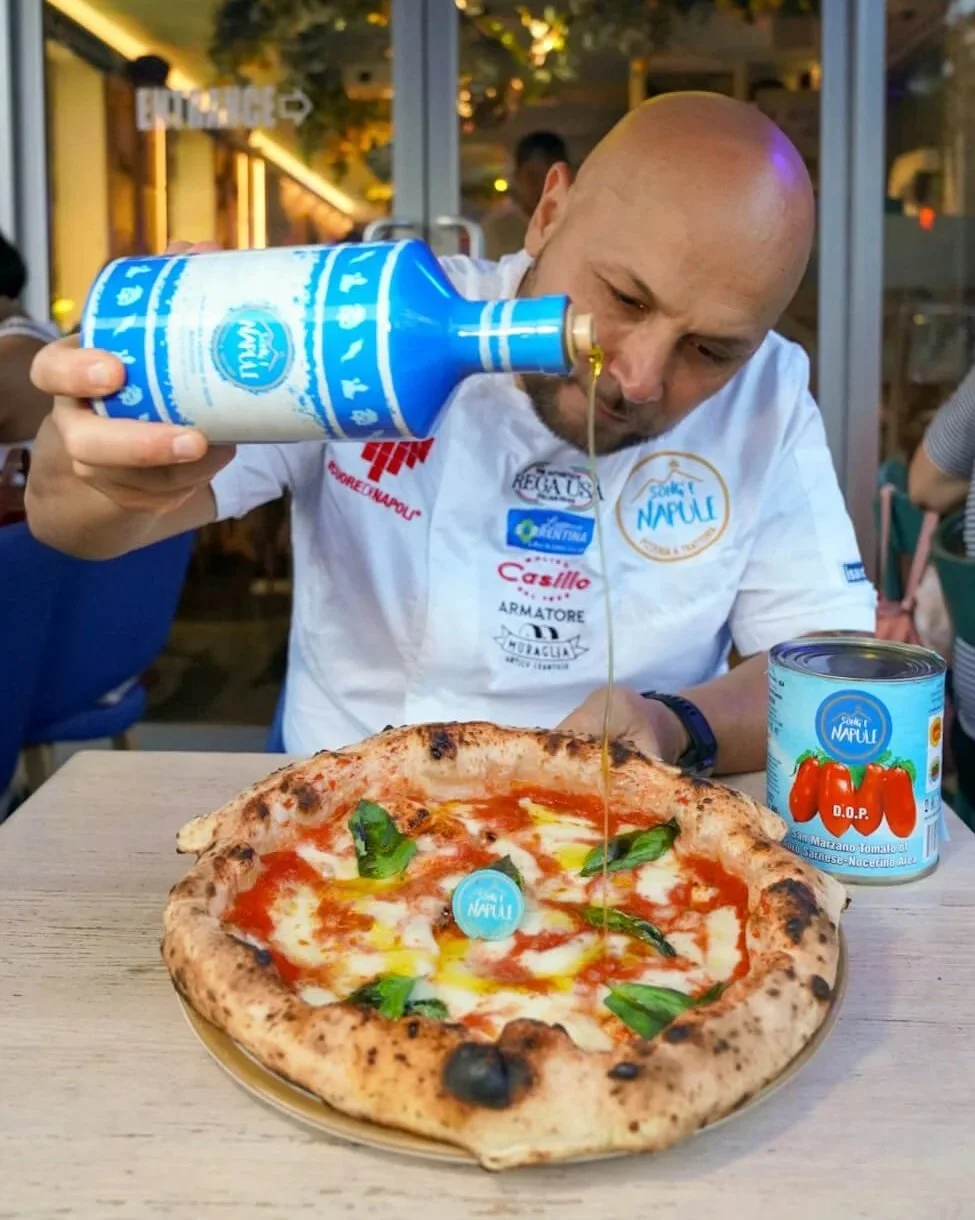 Ciro pouring Extra Virgin Olive Oil on a margherita pizza