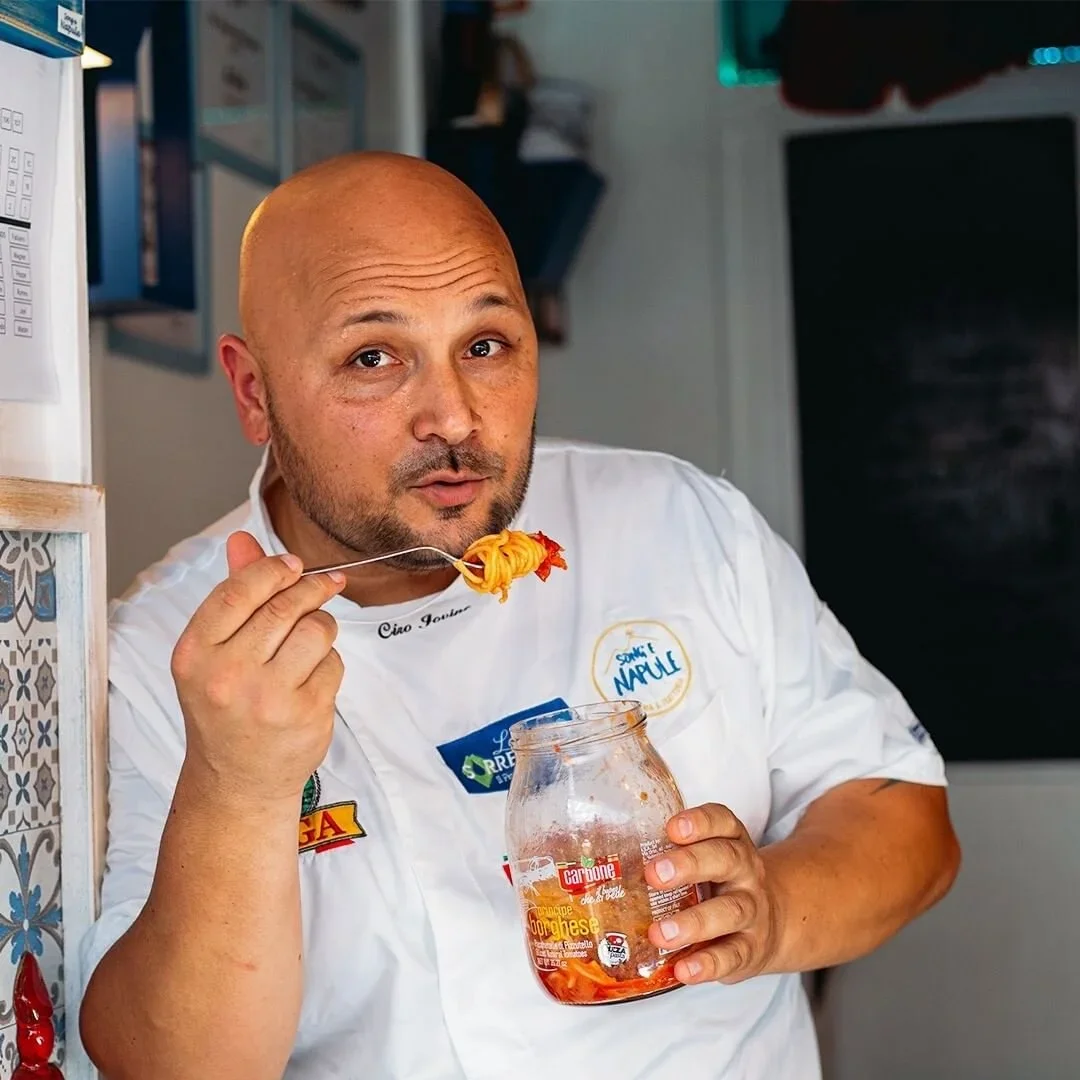 Chef Ciro Iovine tasting some spaghetti pomodoro from a tomato sauce glass bottle