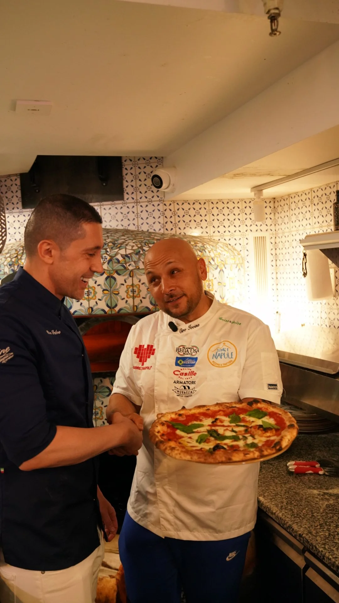 Ciro teaching to a young man holding a finished margherita