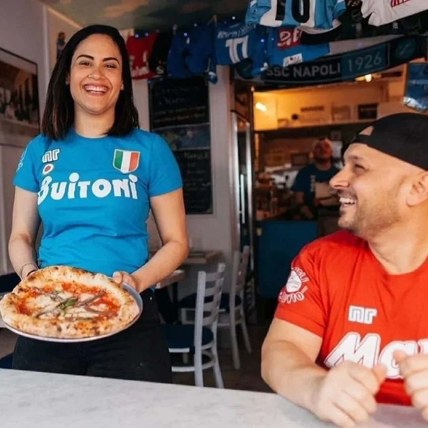 Austria smiling bringing a margherita to share with Ciro, smiling too