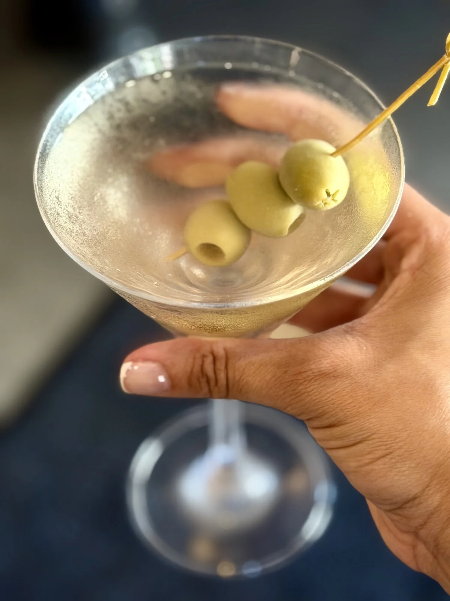 Hands holding a chilled dirty martini
