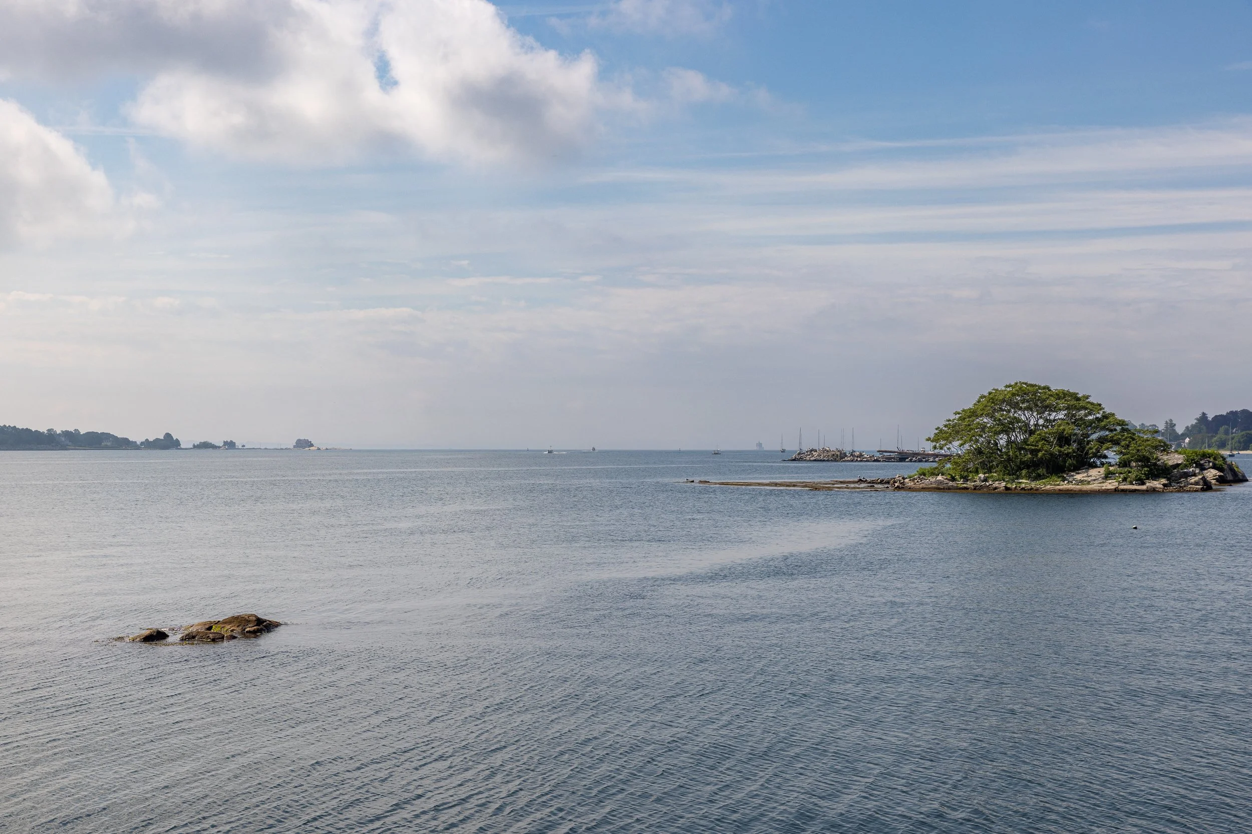 A wind-shaped tree gives tiny Powder Island a recognizable silhouette in the lower Thames River. Beyond Groton’s forts and submarines, scenes like this reveal a waterway experienced simply as a place to sail, swim, and explore.