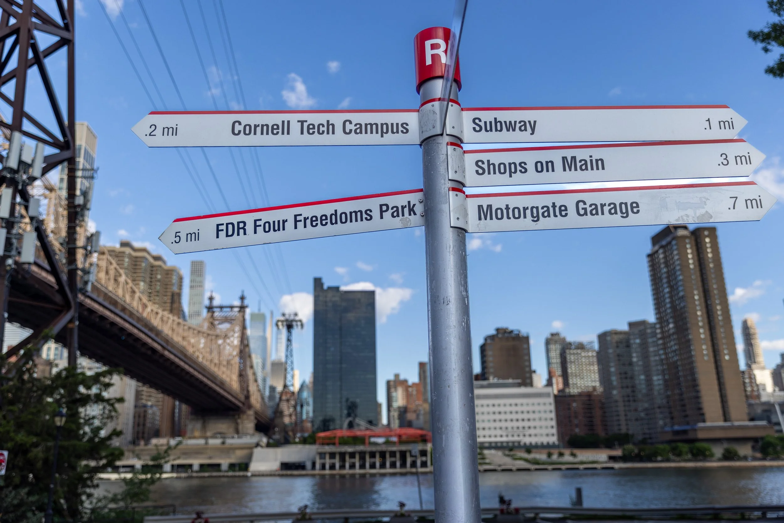 A signpost points toward the subway, Main Street, Cornell Tech, Motorgate and Four Freedoms Park. On an island only two miles long, almost everything is walkable — one of the original plan’s most enduring ideas.