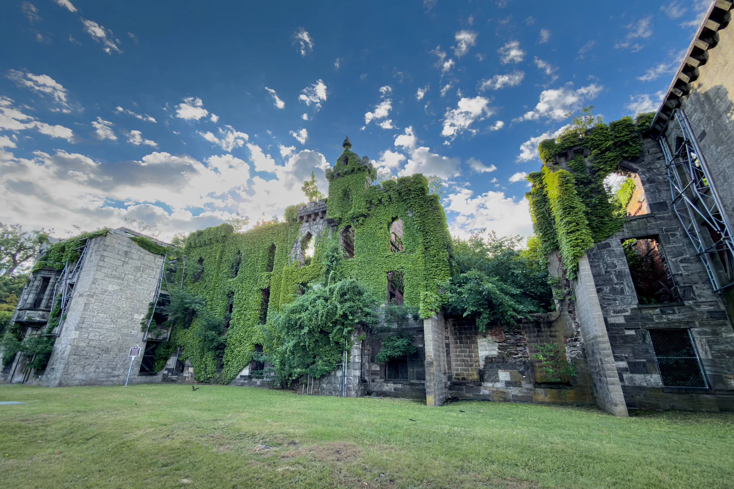 Ivy-covered stone walls of the former Smallpox Hospital stand roofless on a grassy lawn on Roosevelt Island.
