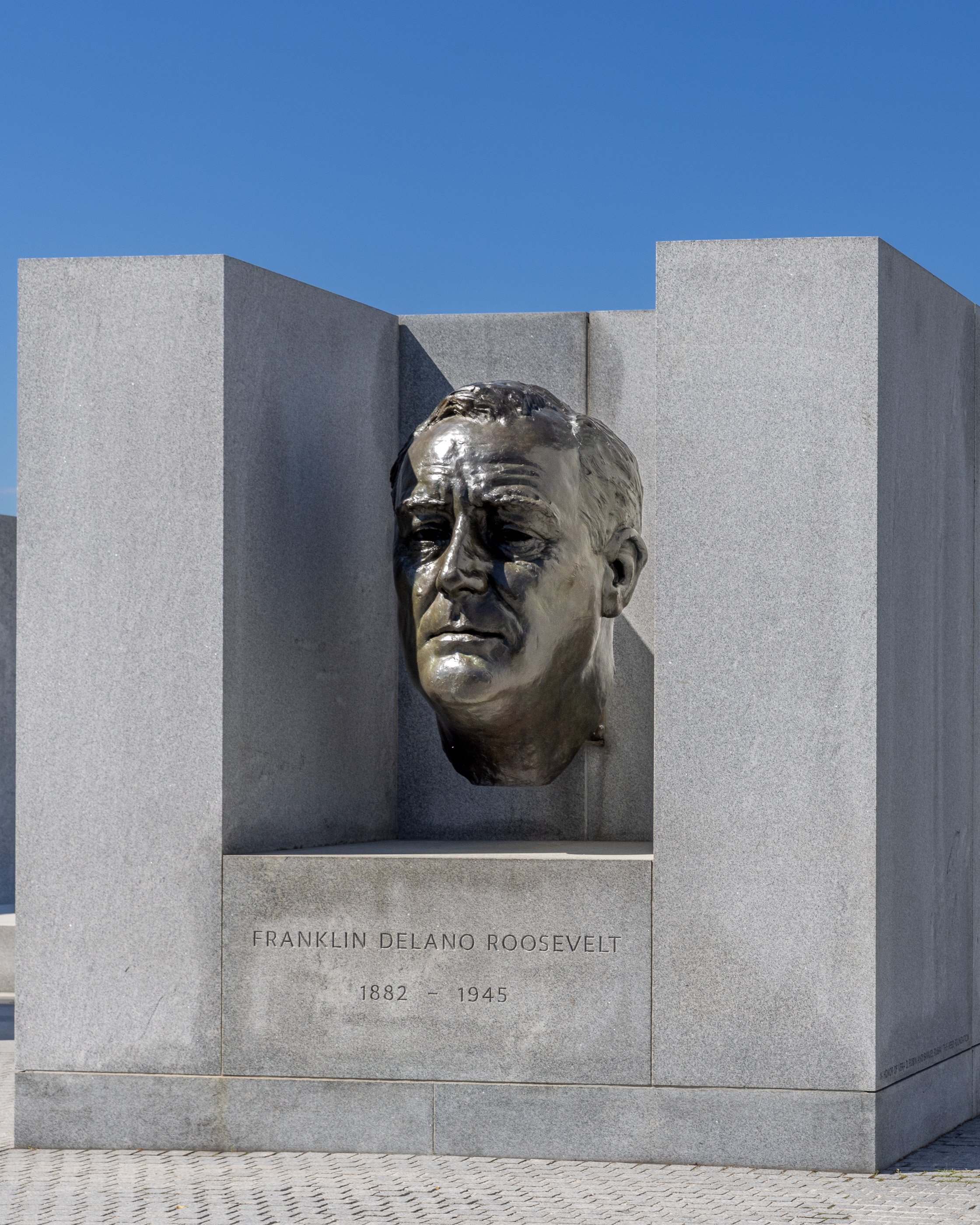 A bronze portrait of Franklin D. Roosevelt sits within Louis Kahn’s Four Freedoms Park. Its formal presentation contrasts with another Roosevelt memorial farther north that depicts him openly using the wheelchair he largely kept from public view.