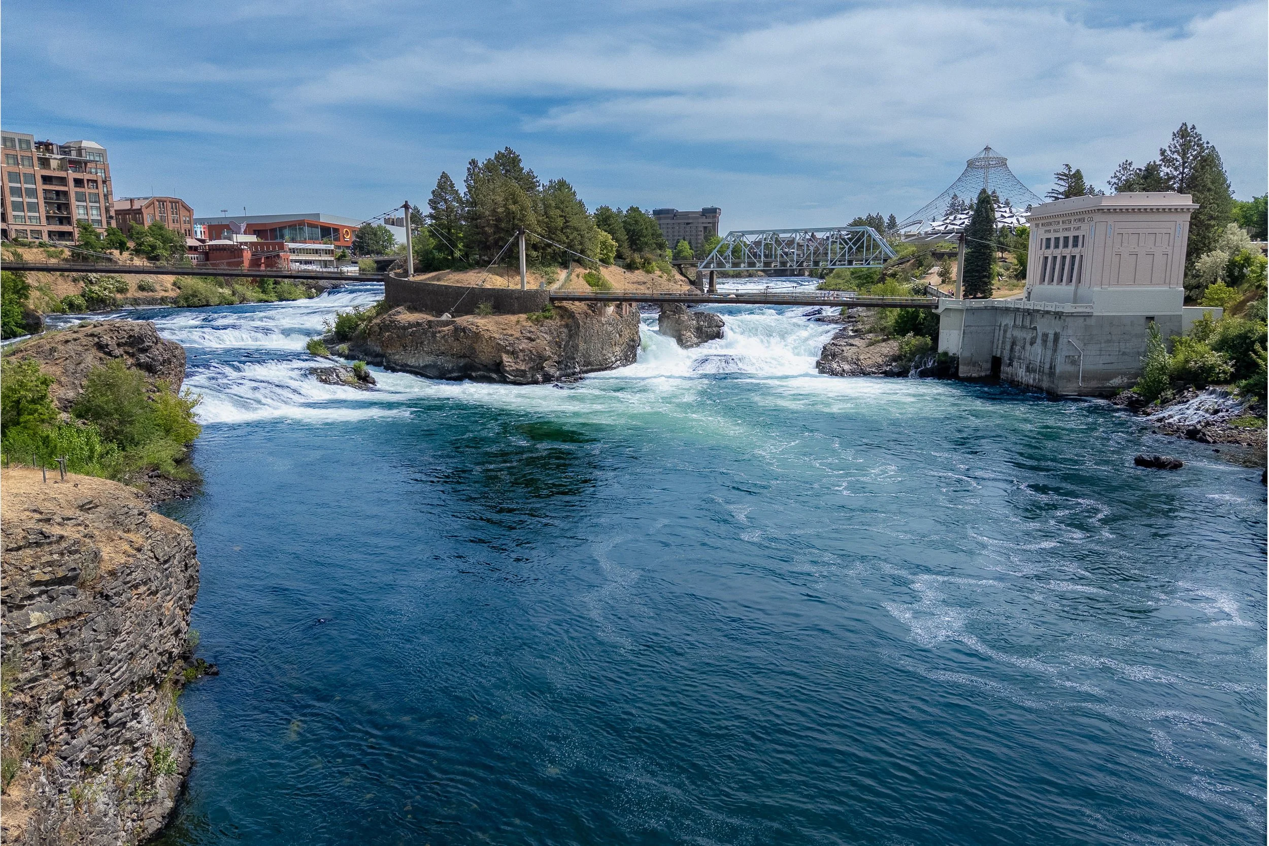 Upper Spokane Falls flowing through basalt channels, with the white Upper Falls Power Plant beside the river.