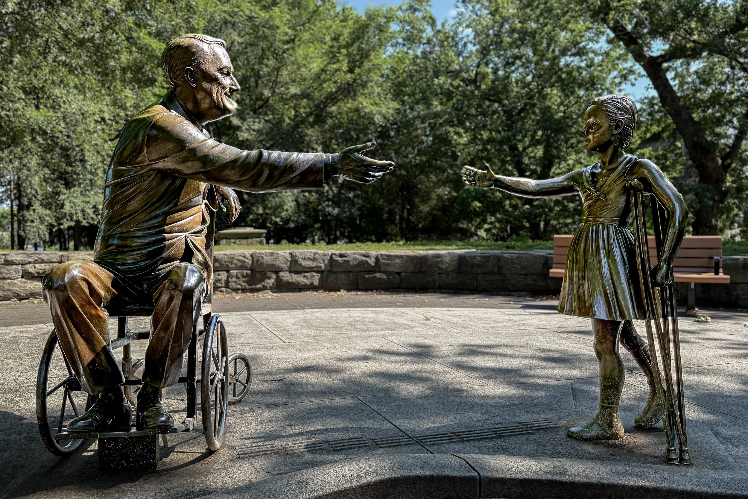 A bronze Franklin D. Roosevelt in a wheelchair reaches toward a young girl on crutches on Roosevelt Island.