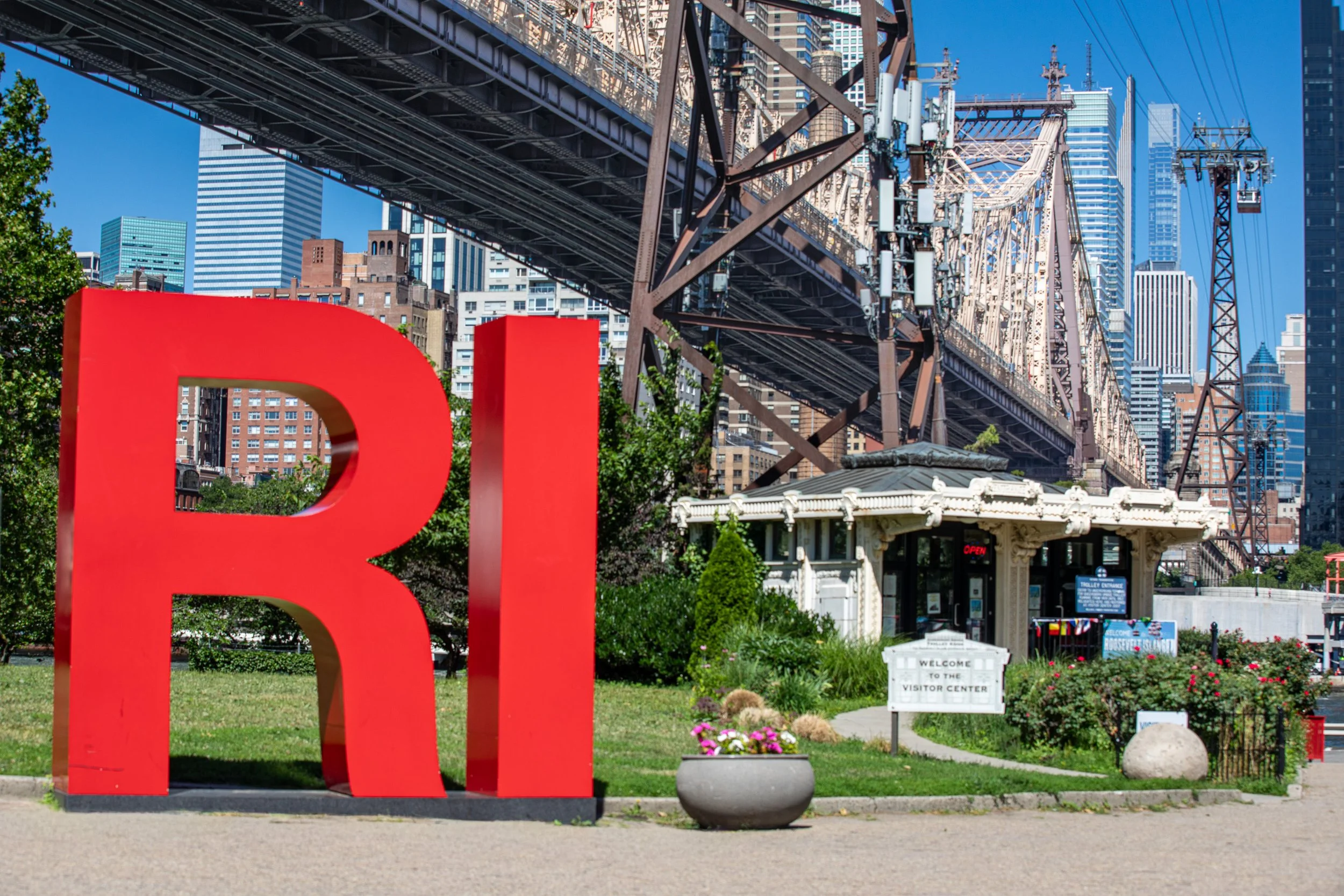 The giant RI letters greet visitors beside the tram terminal, beneath the Queensboro Bridge. When that bridge opened in 1909, it crossed directly over the island — but gave the people below no way to reach it.