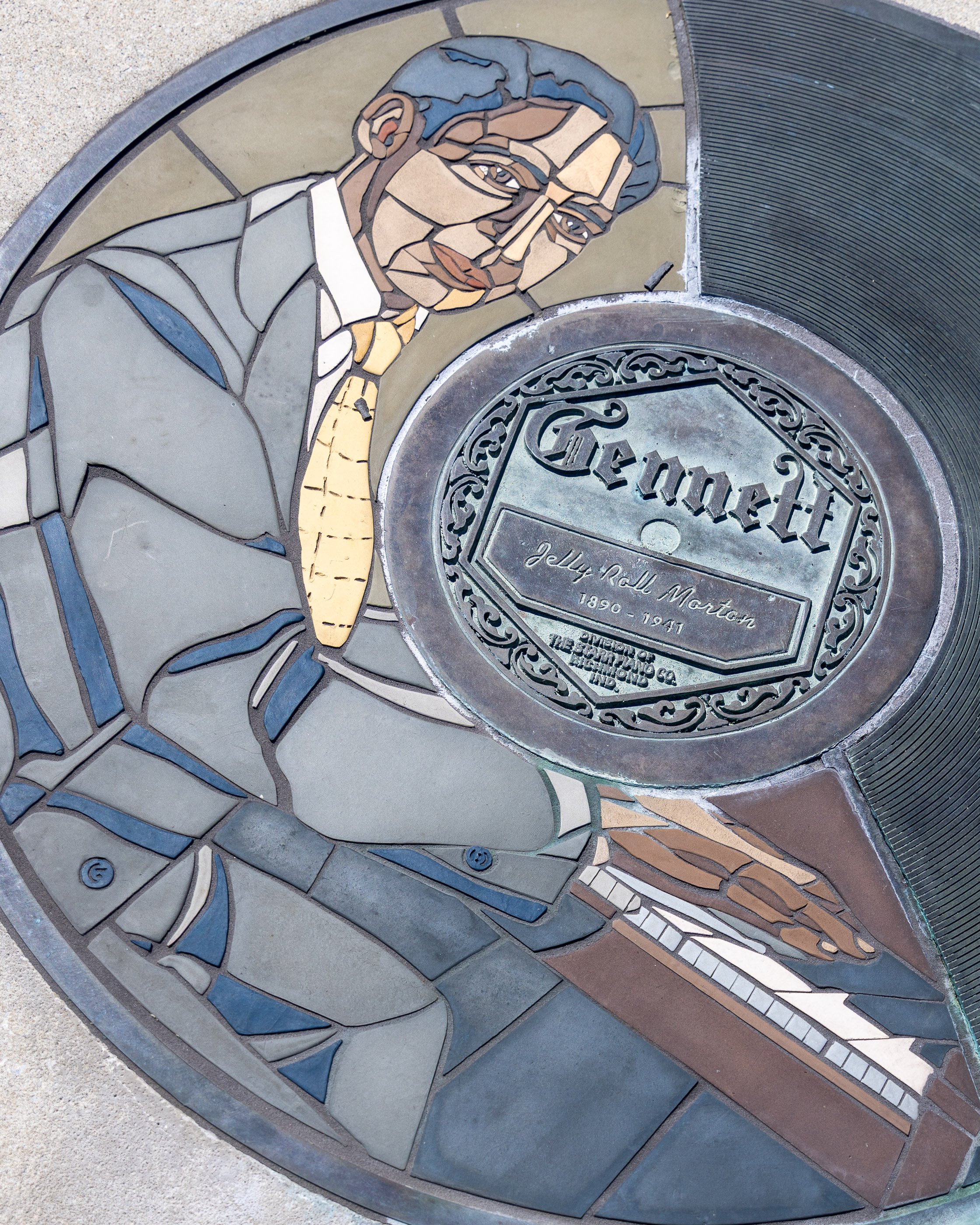 A circular Jelly Roll Morton Walk of Fame marker set into the path and designed like a Gennett record label.