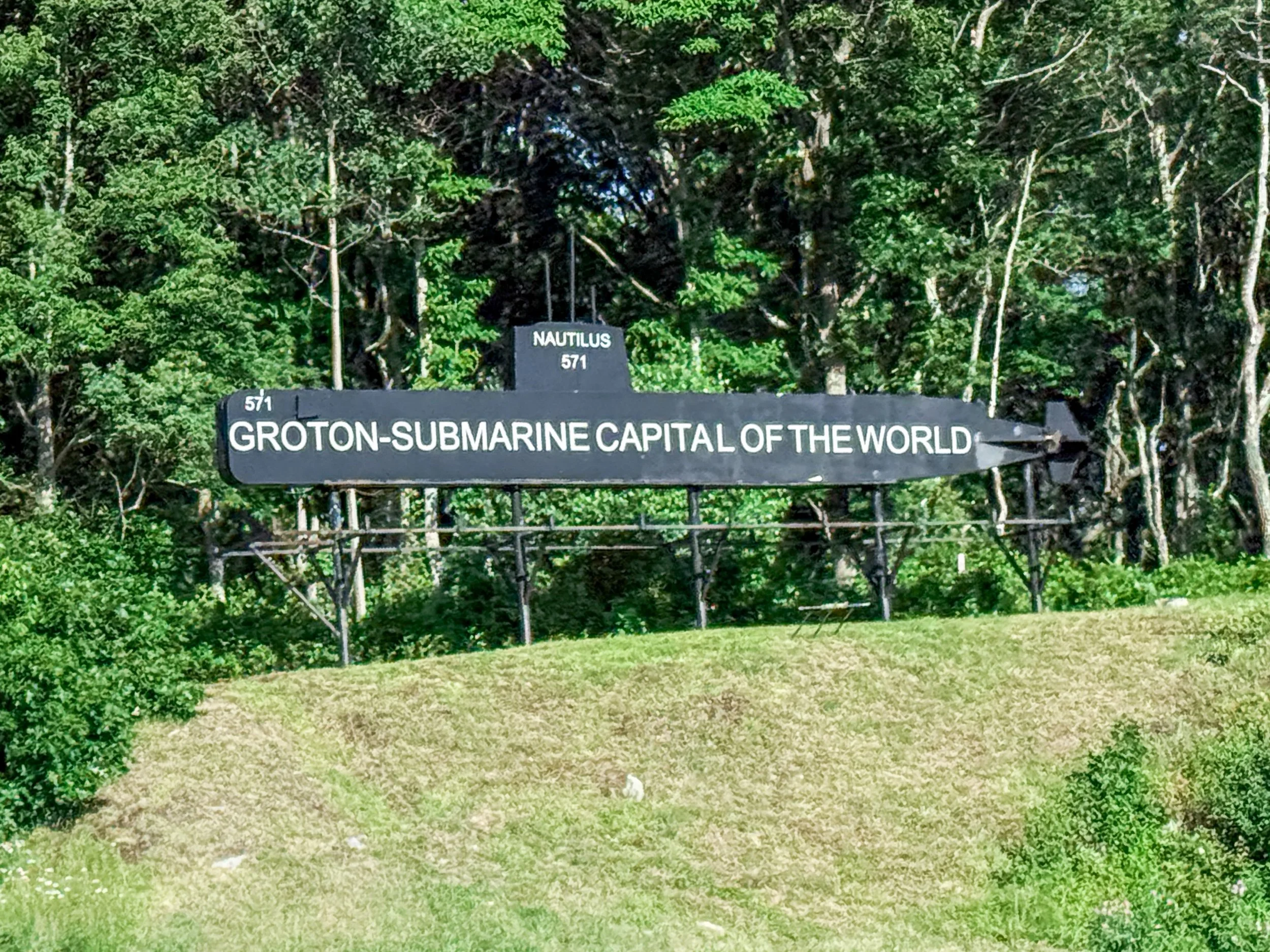 A roadside sign welcomes visitors to Groton, the Submarine Capital of the World, beneath a silhouette marked 571. The title grew from more than a century of intertwined decisions by Electric Boat, the U.S. Navy, engineers, workers, and the town itsel