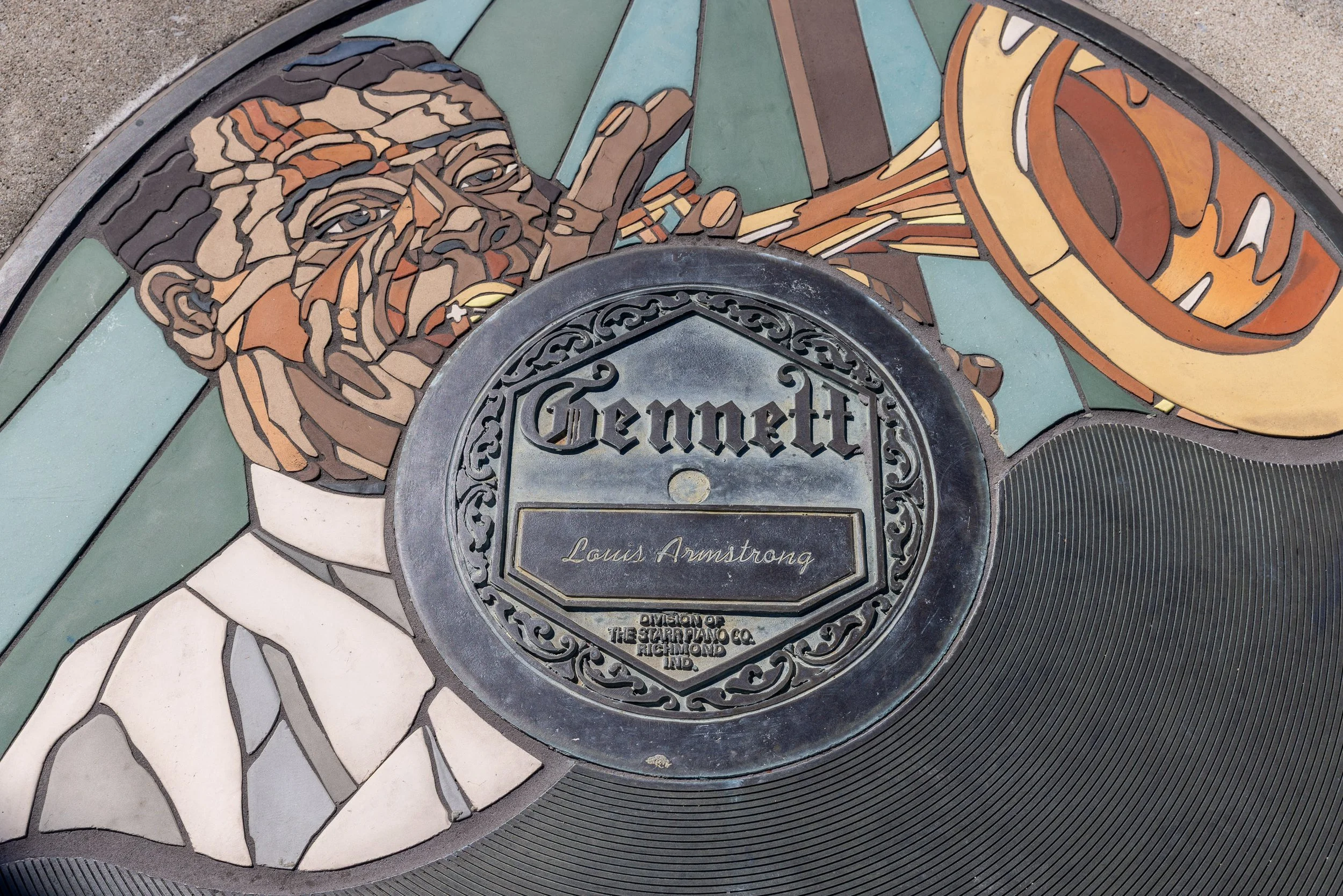 A circular Louis Armstrong Walk of Fame marker set into the path and designed like a Gennett record label.