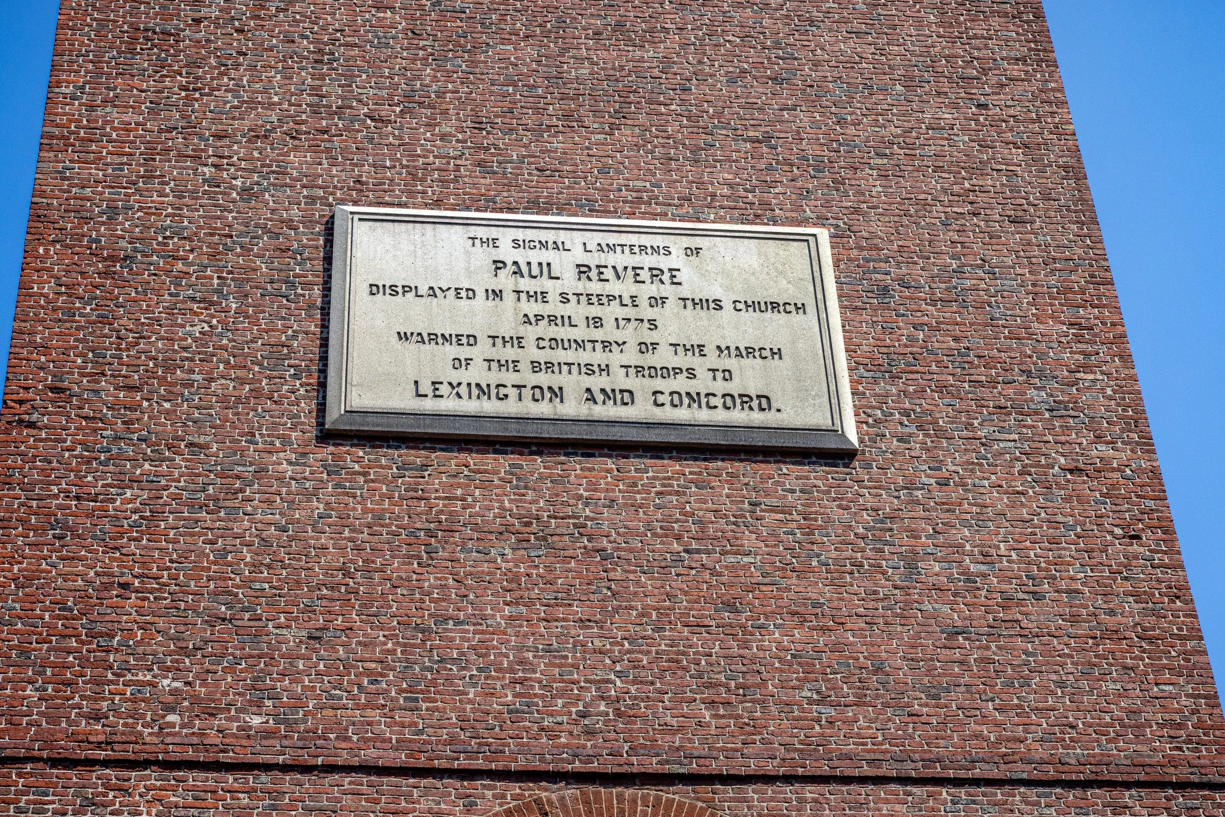 A stone plaque on Old North Church calls them “the signal lanterns of Paul Revere.” Revere arranged the signal. The plaque does not name the men who climbed the tower to display it.