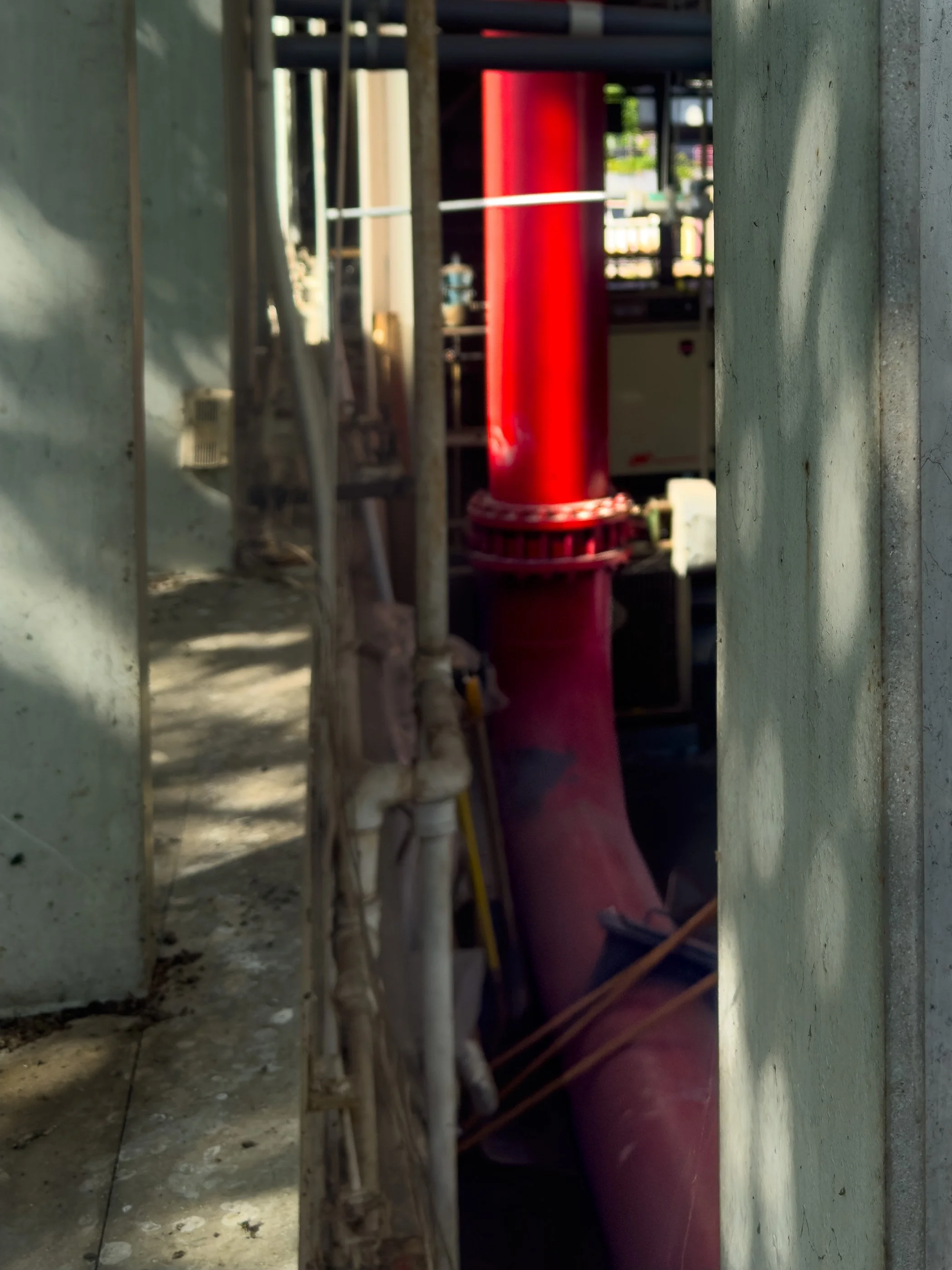 A large red pipe runs through concrete supports inside Roosevelt Island’s pneumatic waste facility.