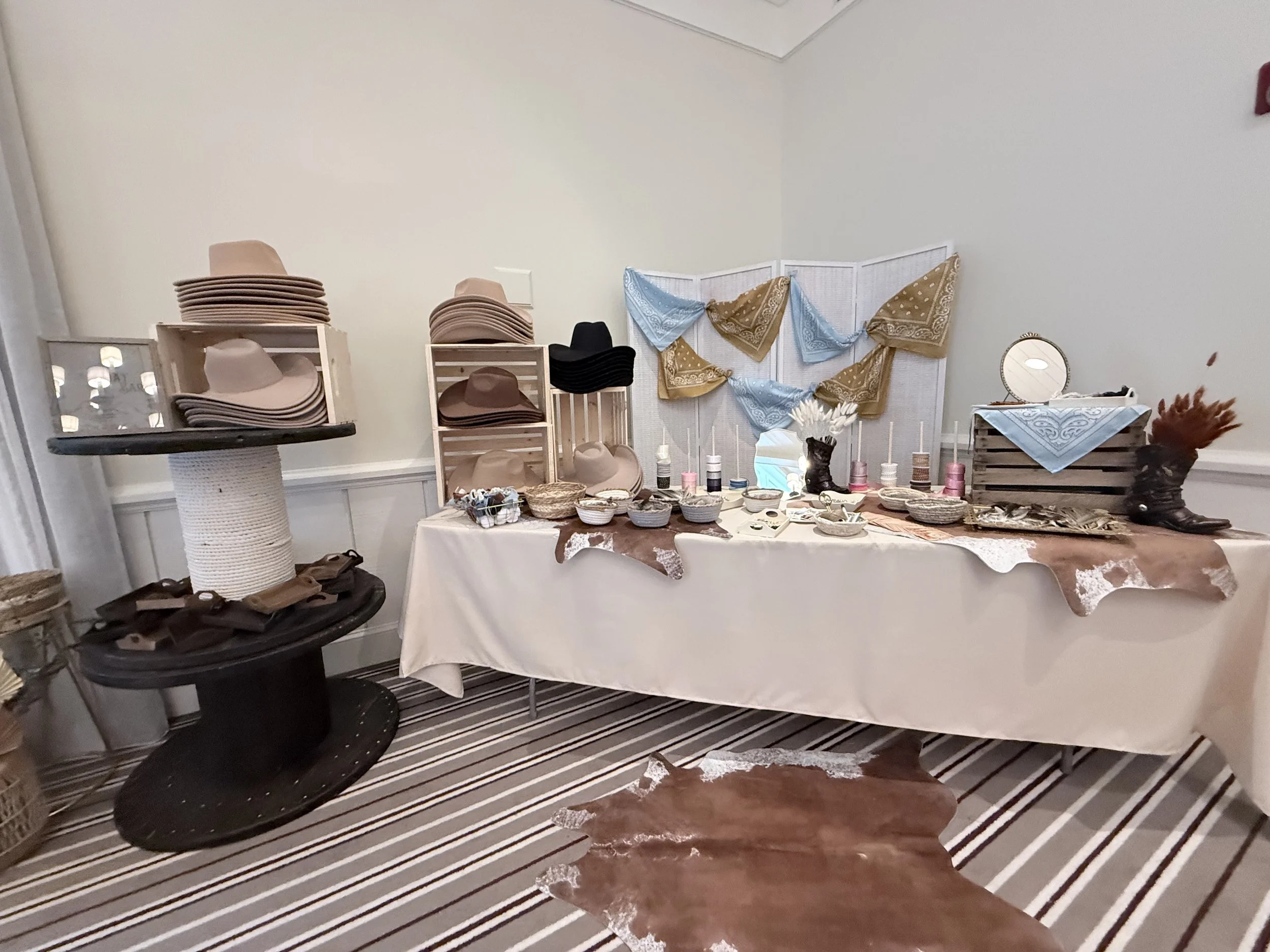Display of hats, bandanas, and accessories arranged on shelves and a table at a craft or thrift store, with a mirror and decorative items in the background.