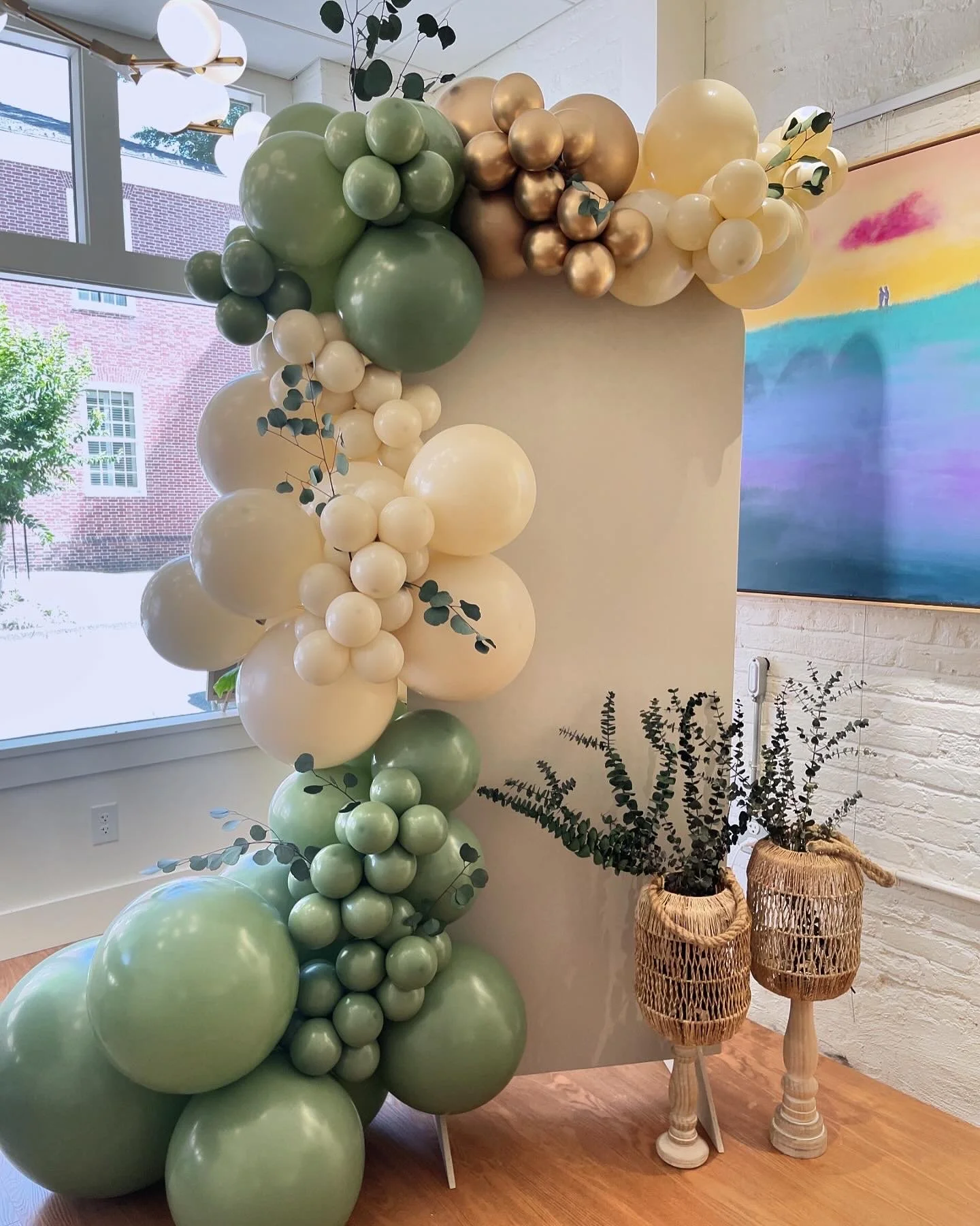 Green, ivory, and gold balloon garland installation by Wildly Pretty Events