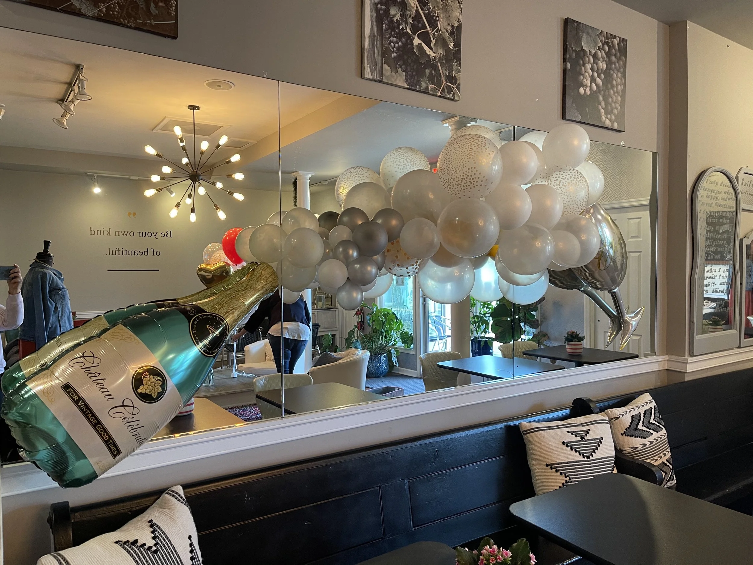 Champagne bottle balloon sculpture with a metallic organic balloon garland in a restaurant lounge