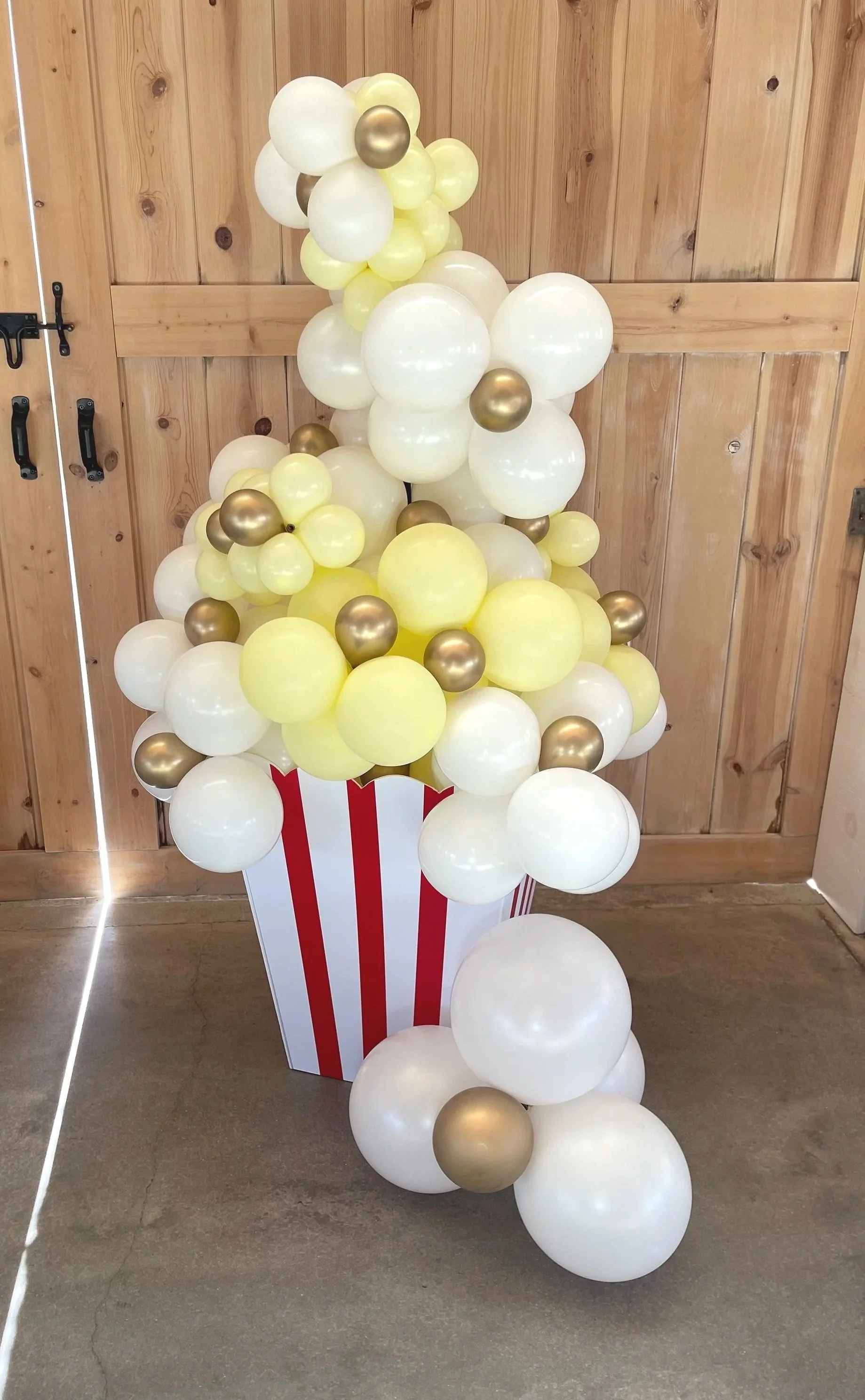 Yellow, white, and gold balloon column shaped like a popcorn bucket for a movie-themed party