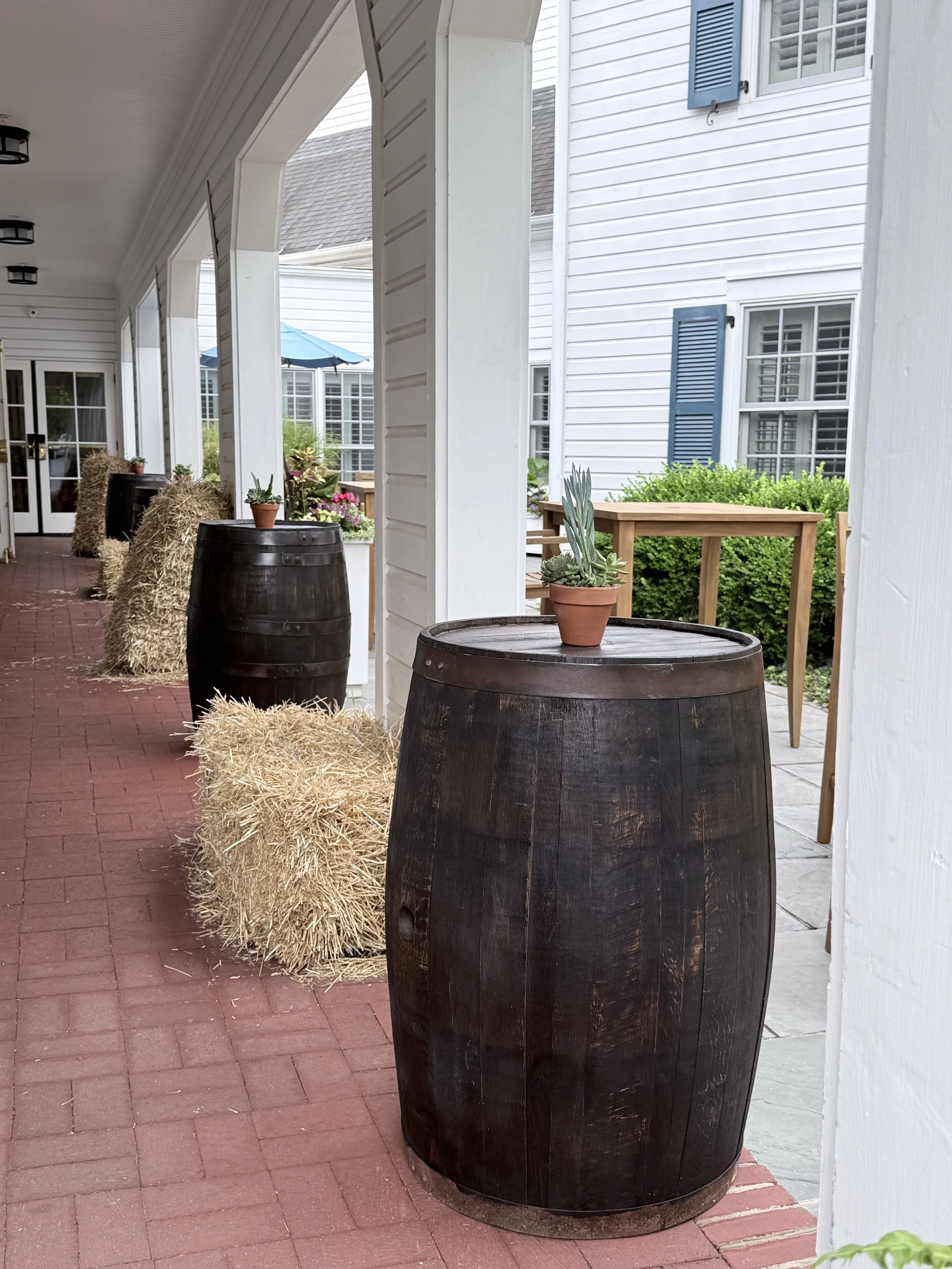 Rustic porch venue decorated with wine barrels and hay bales for an event setup