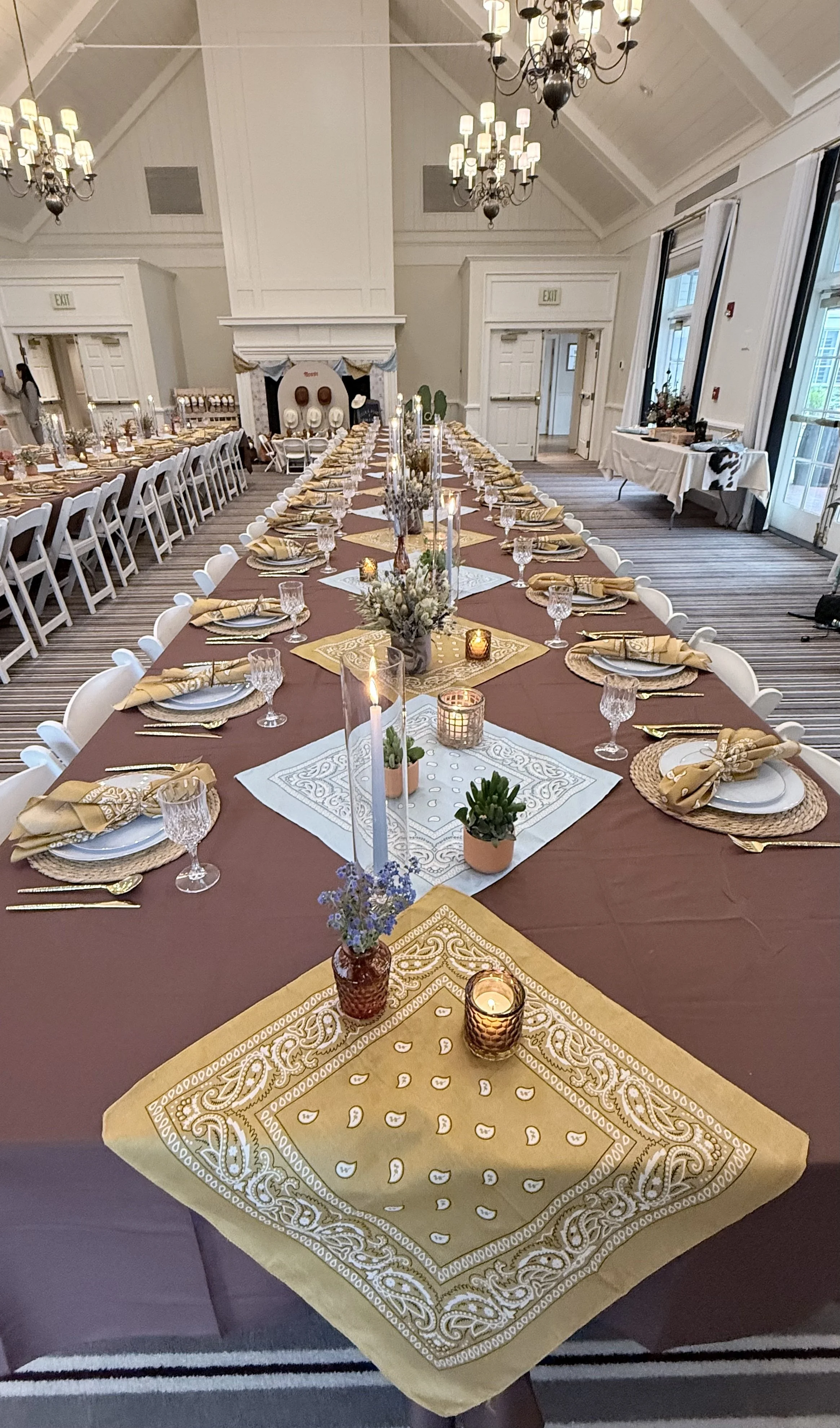 Long formal dinner table with gold and burgundy decor styled for a western-themed baby shower