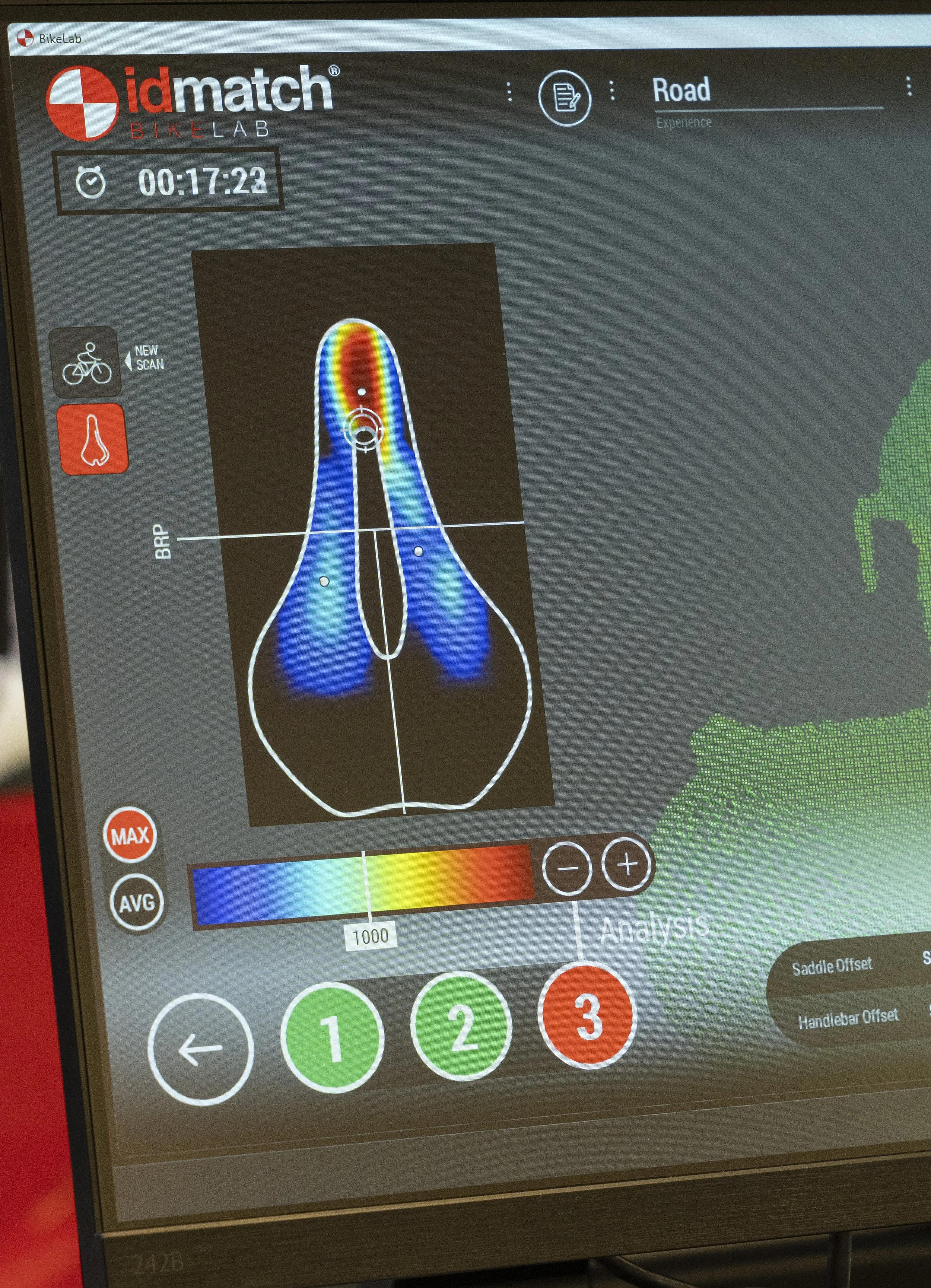 A digital screen displaying a bicycle fitting analysis with a heat map of the rider's foot pressure, a color scale from blue to red indicating pressure levels, and various control buttons for analysis adjustments.