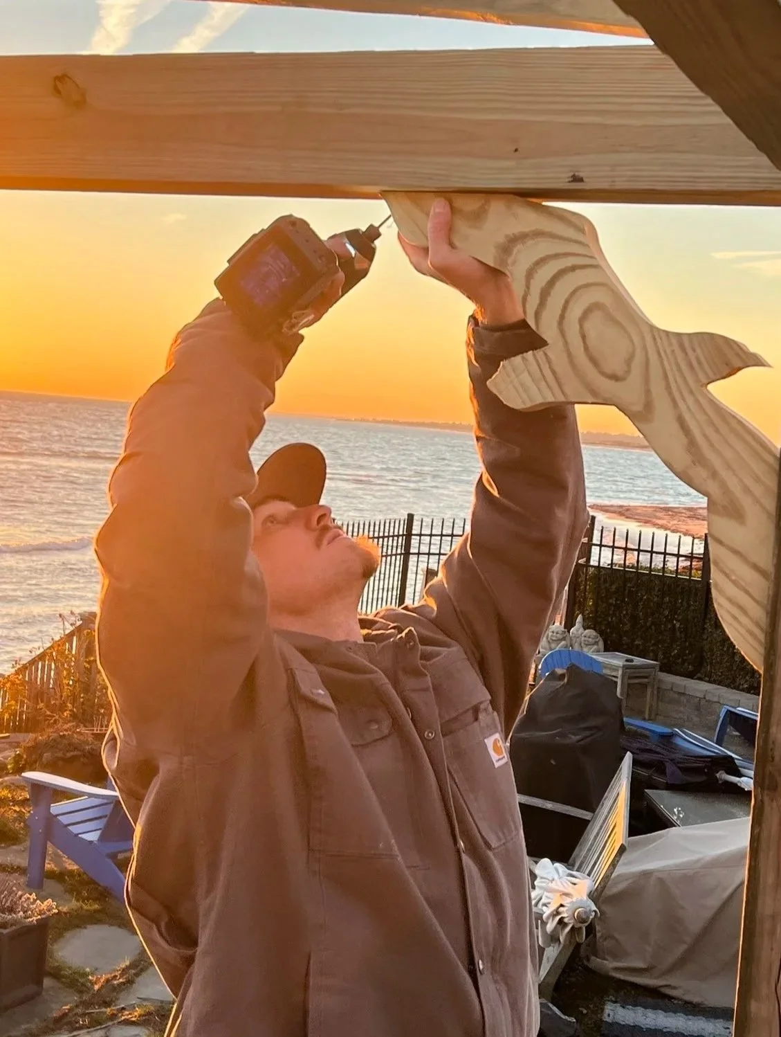 Carpenter installing custom seagull diagonal hurricane brace on artisan pergola in Matunuck RI