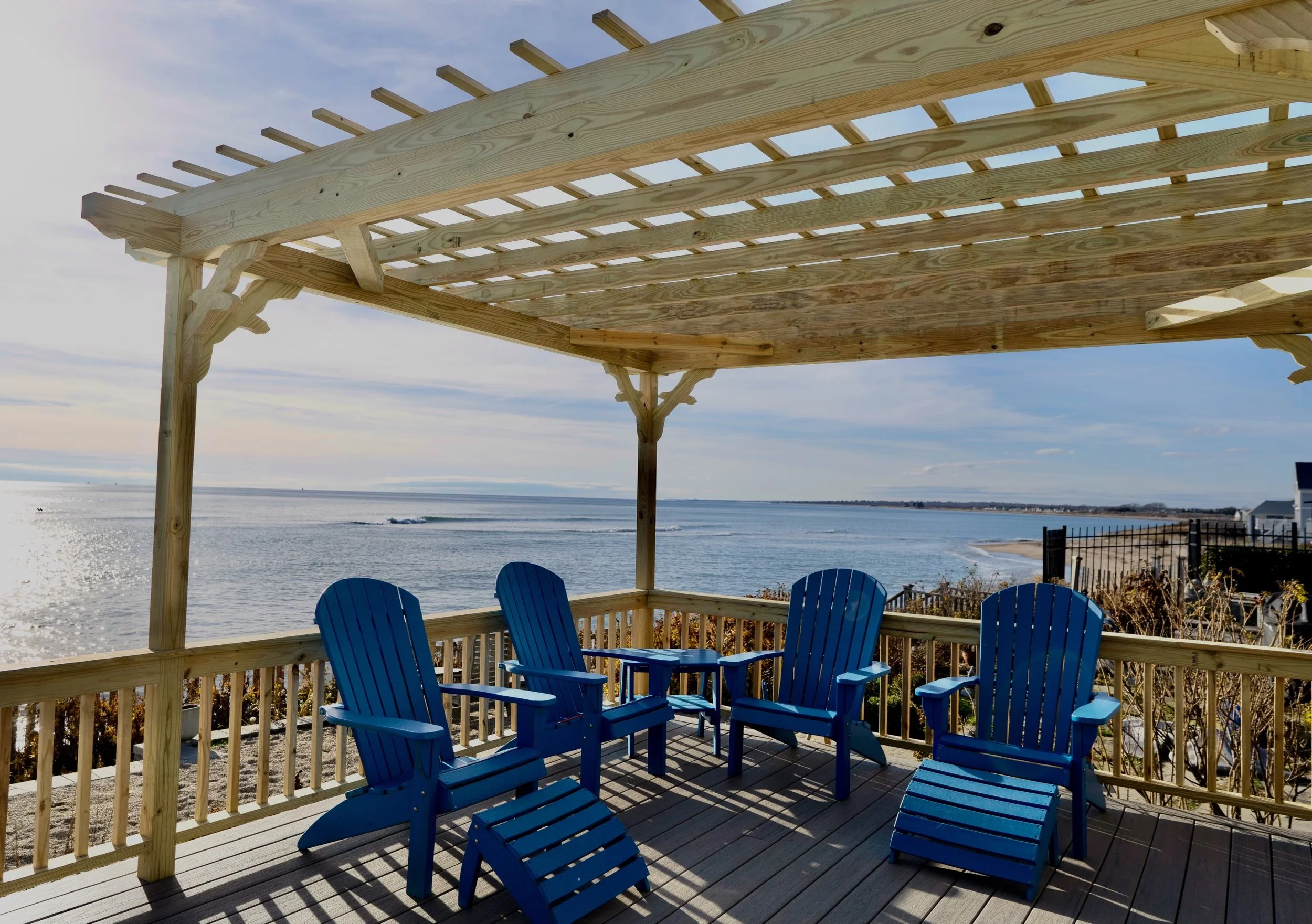 Custom built pergola over coastal deck with arched feature and seagull decorative braces in Matunuck RI