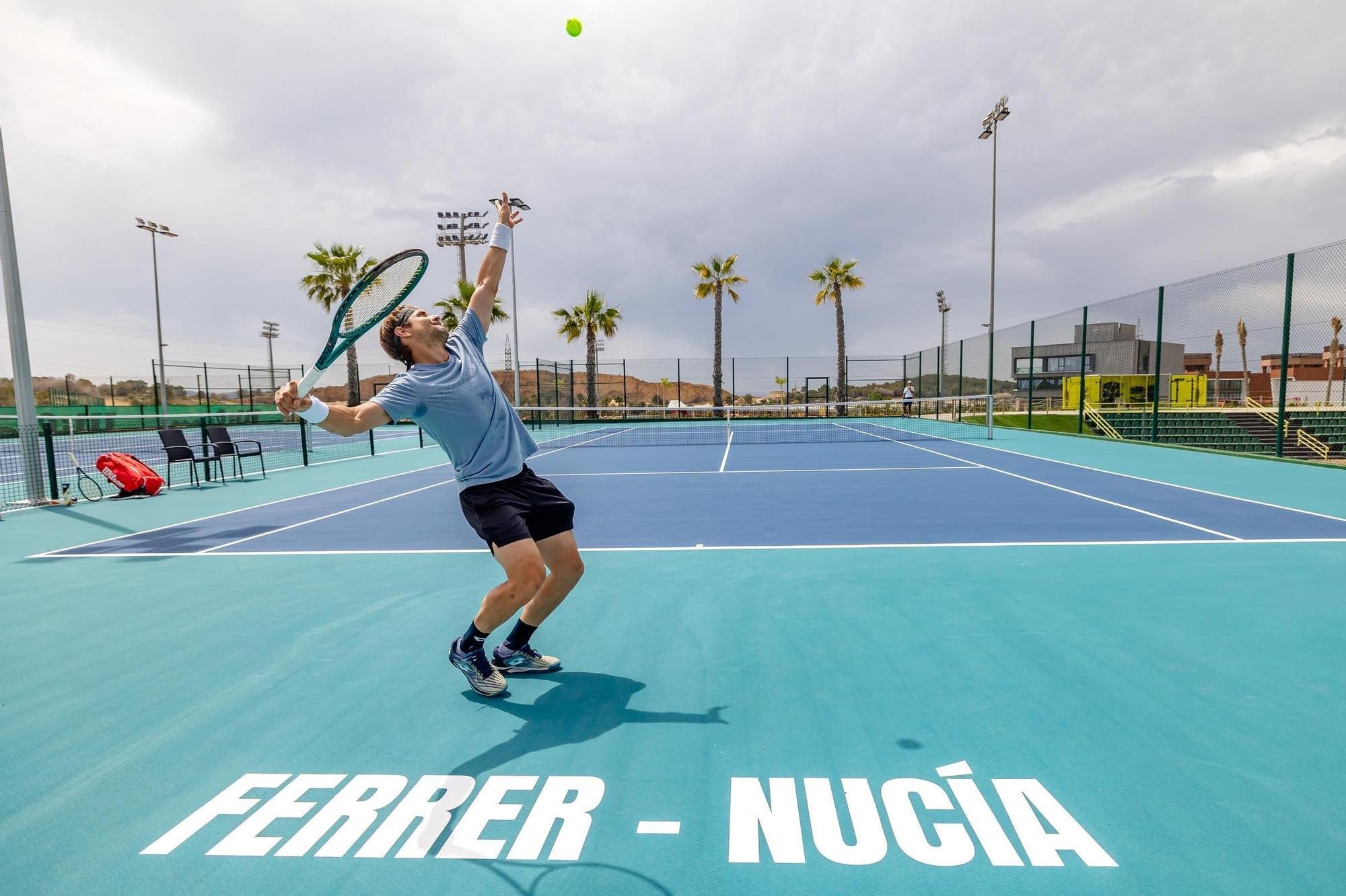 Jugador de tenis en acción en una cancha exterior, preparando para golpear una pelota verde con raqueta.