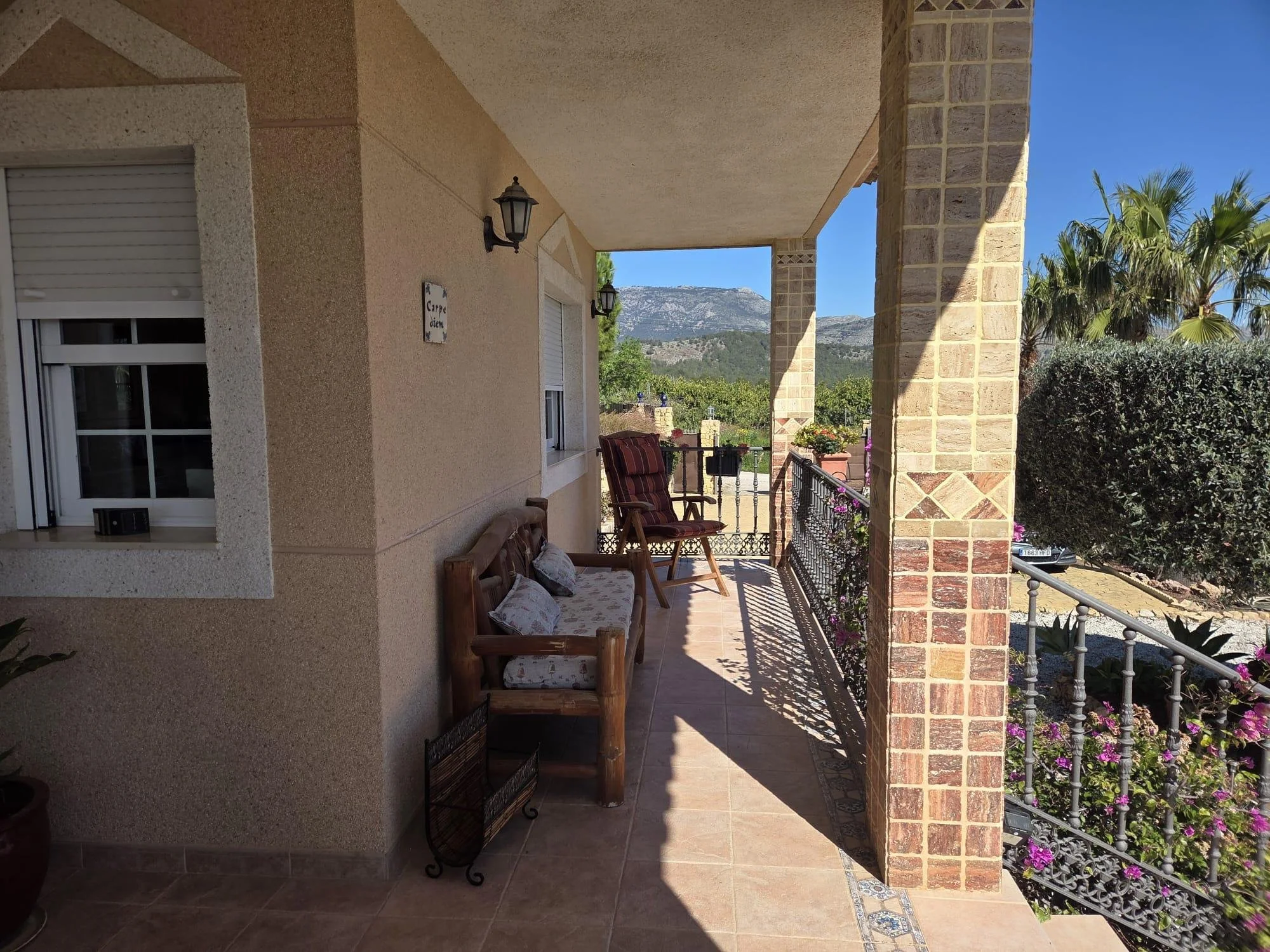 Vista de una terraza con tumbonas, plantas y vista a las montañas bajo un cielo despejado