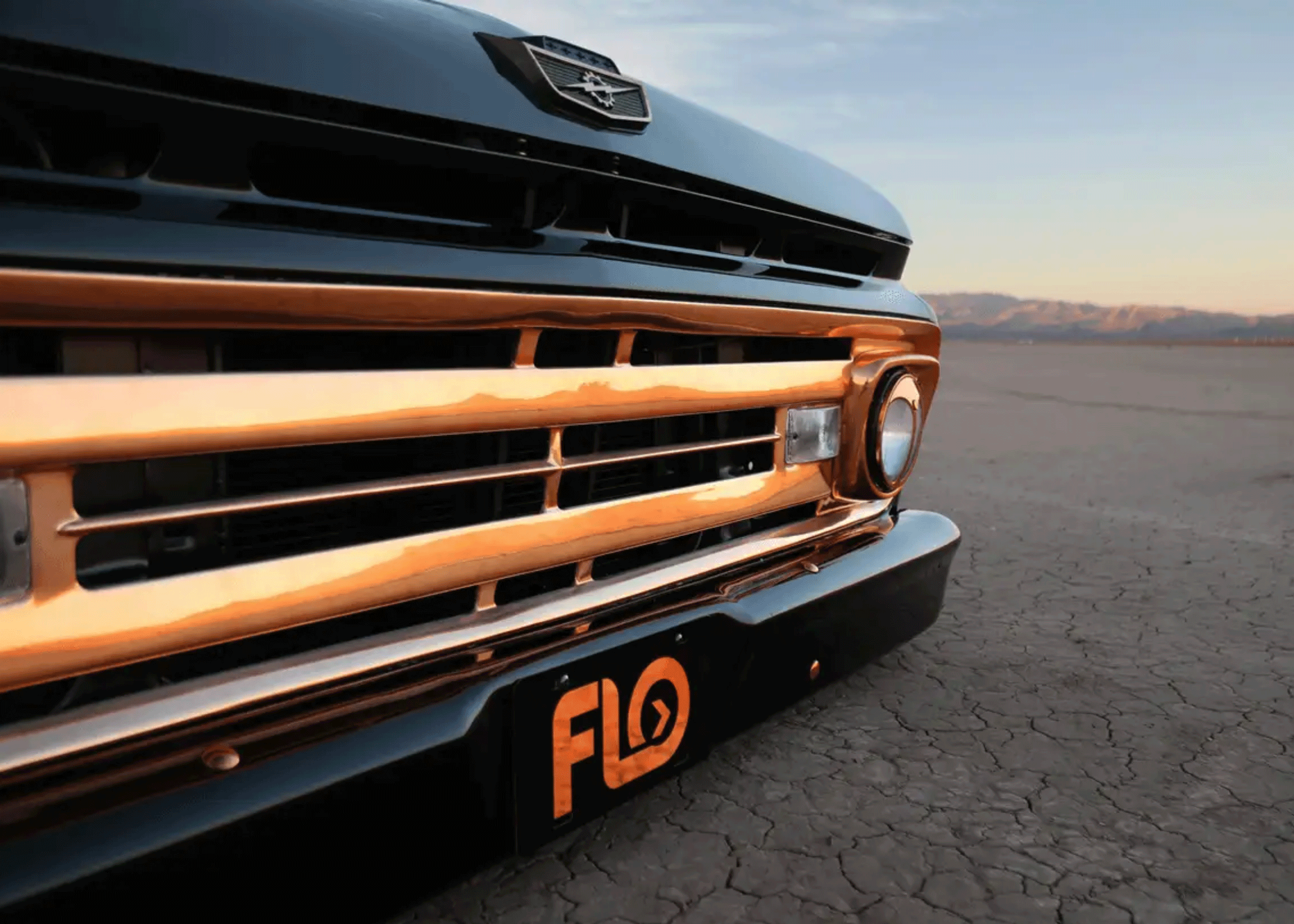 Custom copper front plate depicting FLO Airride logo on the front bumper of a copper-trimmed Ford F-100