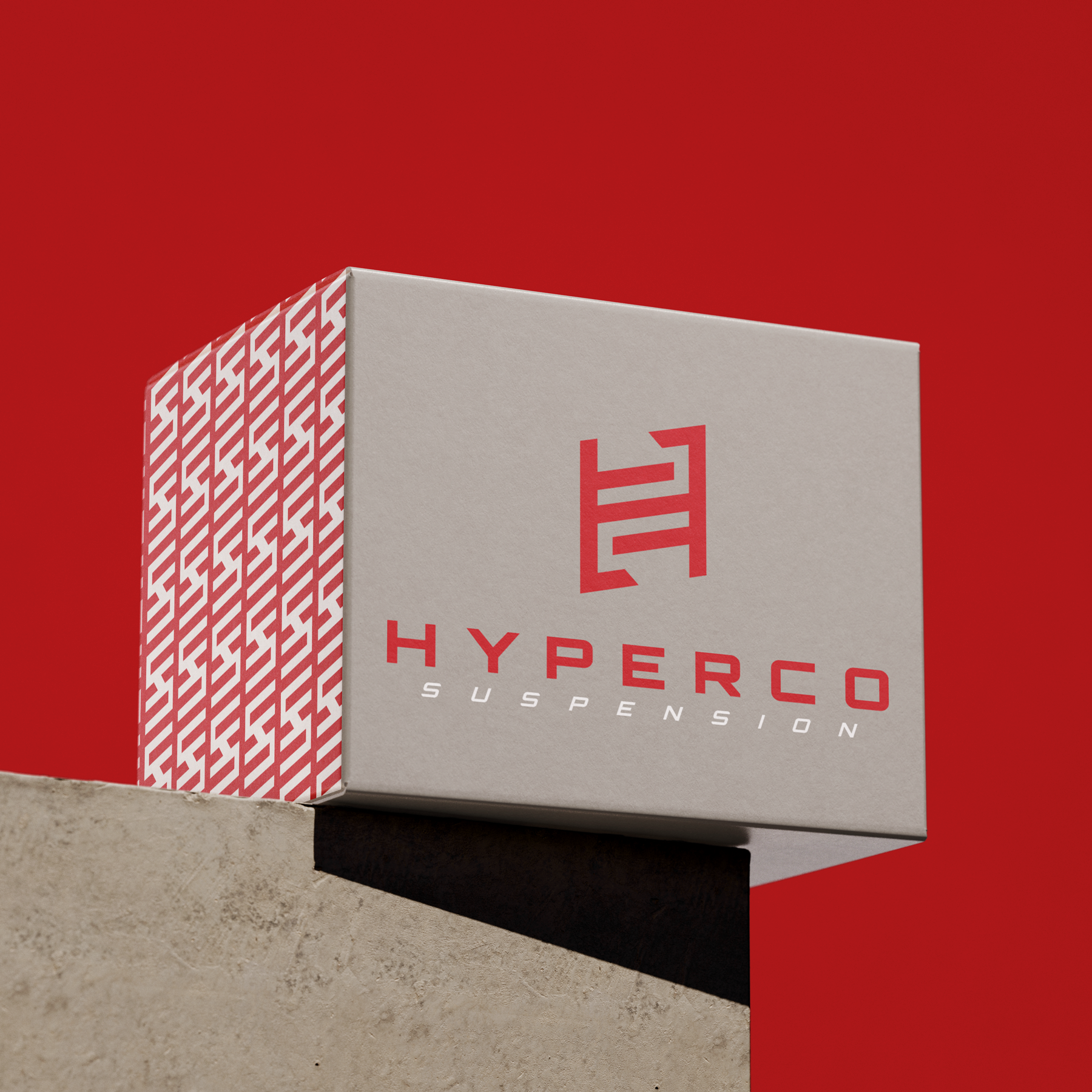Red hyperco suspension logo and icon pattern printed on adjacent sides of product packaging, depicted resting on a concrete corner in front of a red background
