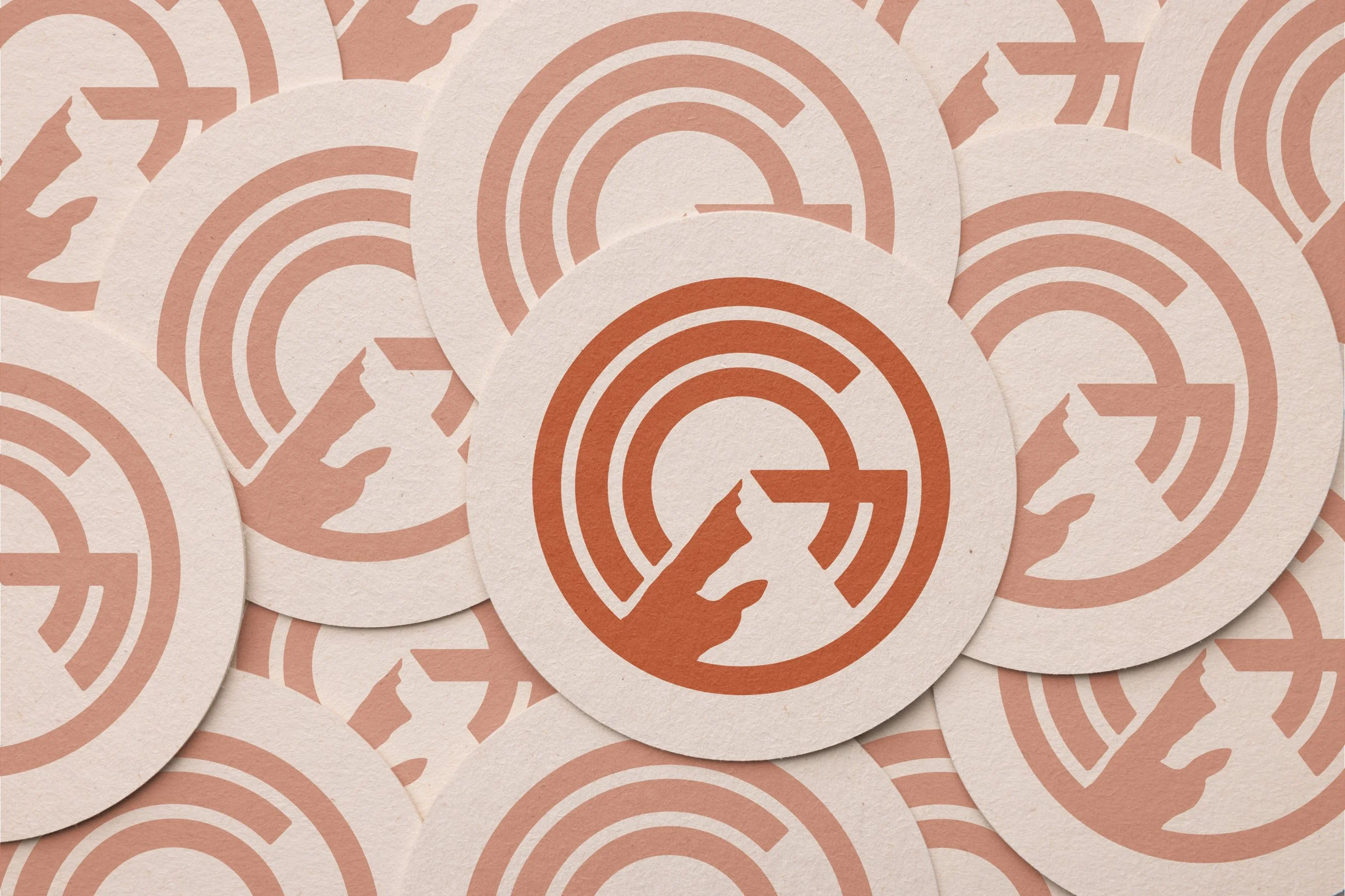 stacked round printed coasters depicting GO Mountain logo icon