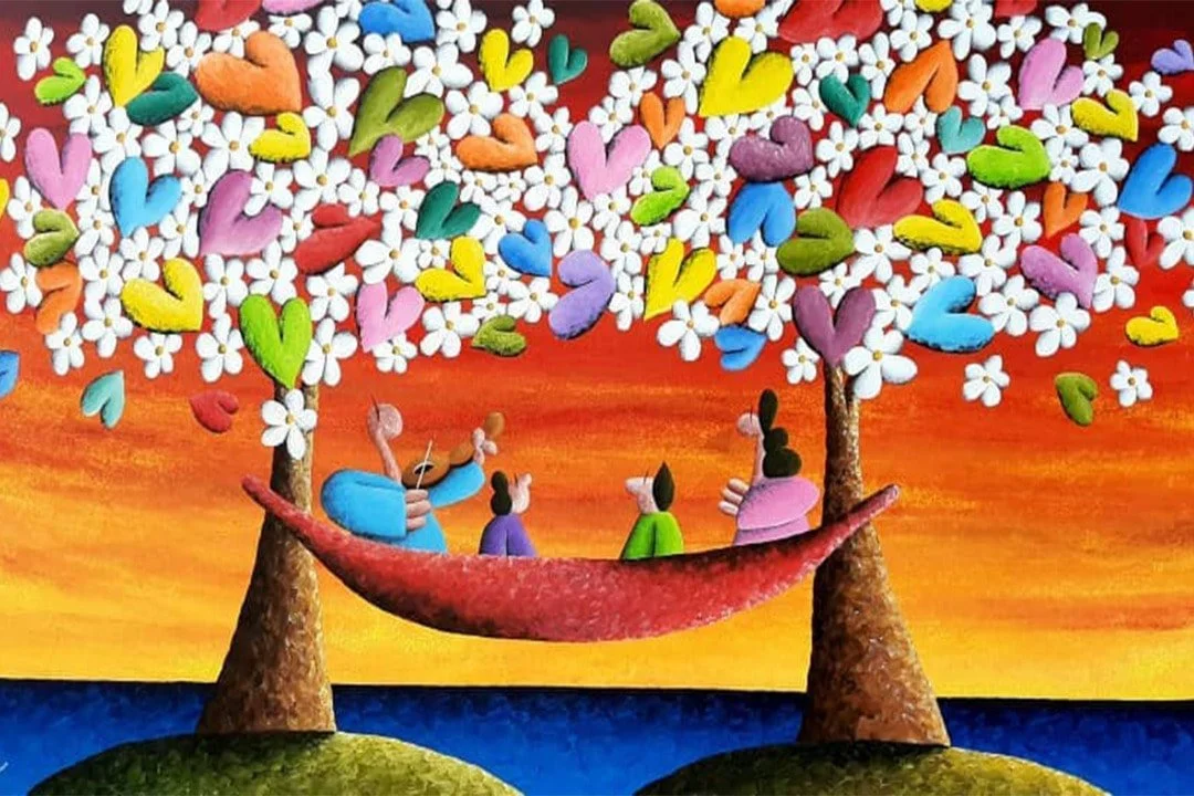Cartoon illustration of four characters sitting in a hammock under two trees with colorful heart-shaped and flower-shaped leaves against a sunset sky over water.