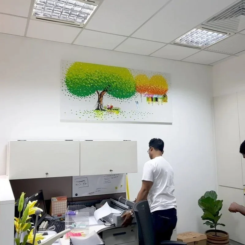 Office workspace with a desk, computer, papers, and a large colorful painting of trees on the ceiling.