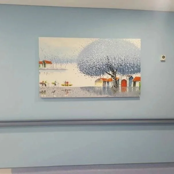 Painting of a winter scene with snow-covered houses, a lake, and a large tree on the riverbank