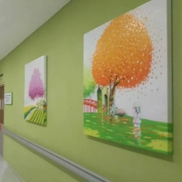Paintings of colorful trees on a green wall in an art gallery.