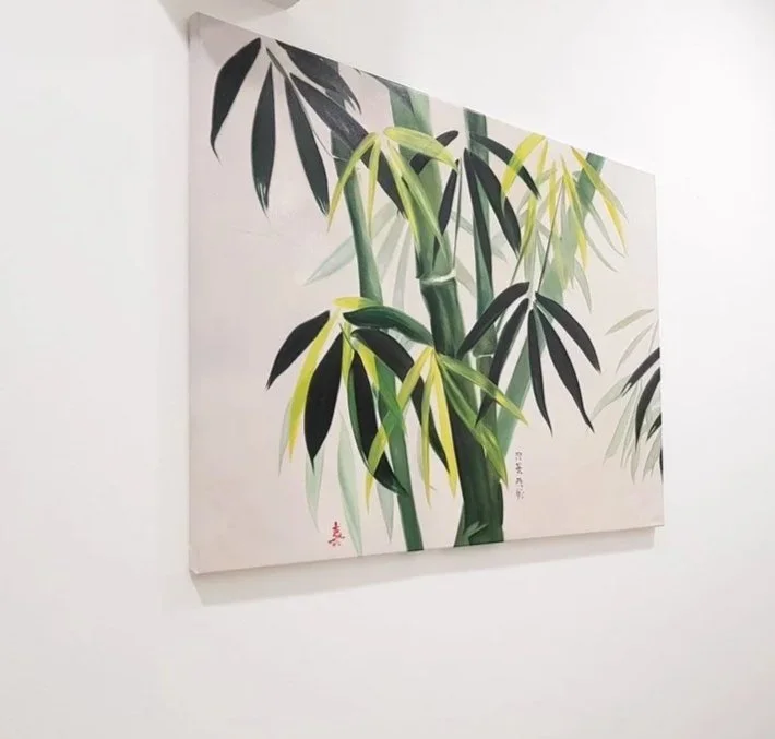 Painting of a bamboo plant with green and black leaves on a white background
