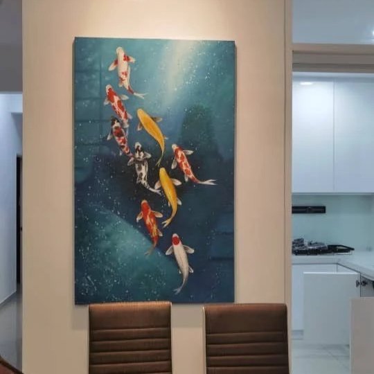 A large painting of koi fish swimming in water, hanging on a white wall above two brown chairs, with a kitchen visible to the right.